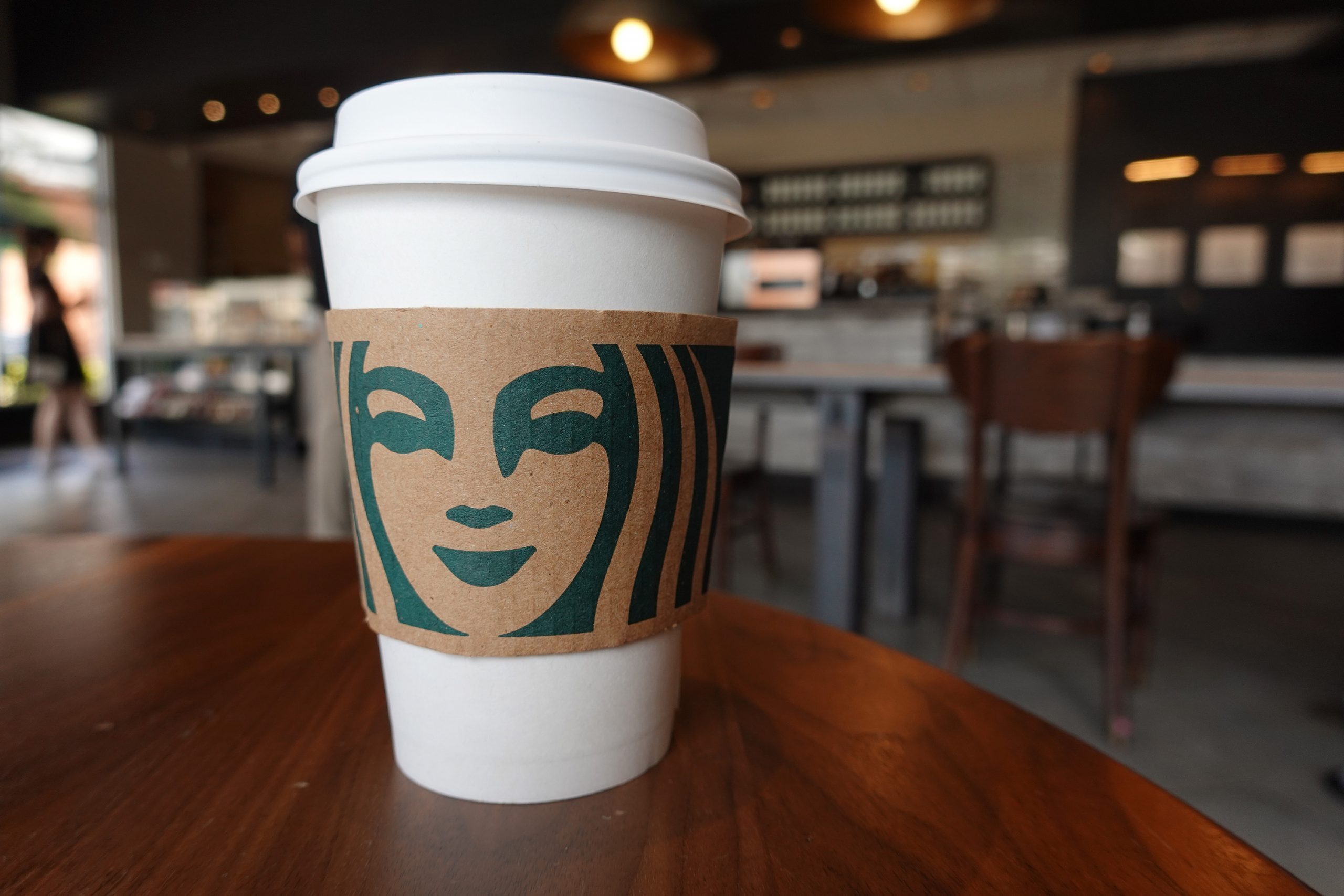 a starbucks cup sits on a table with the cafe out of focus in the background