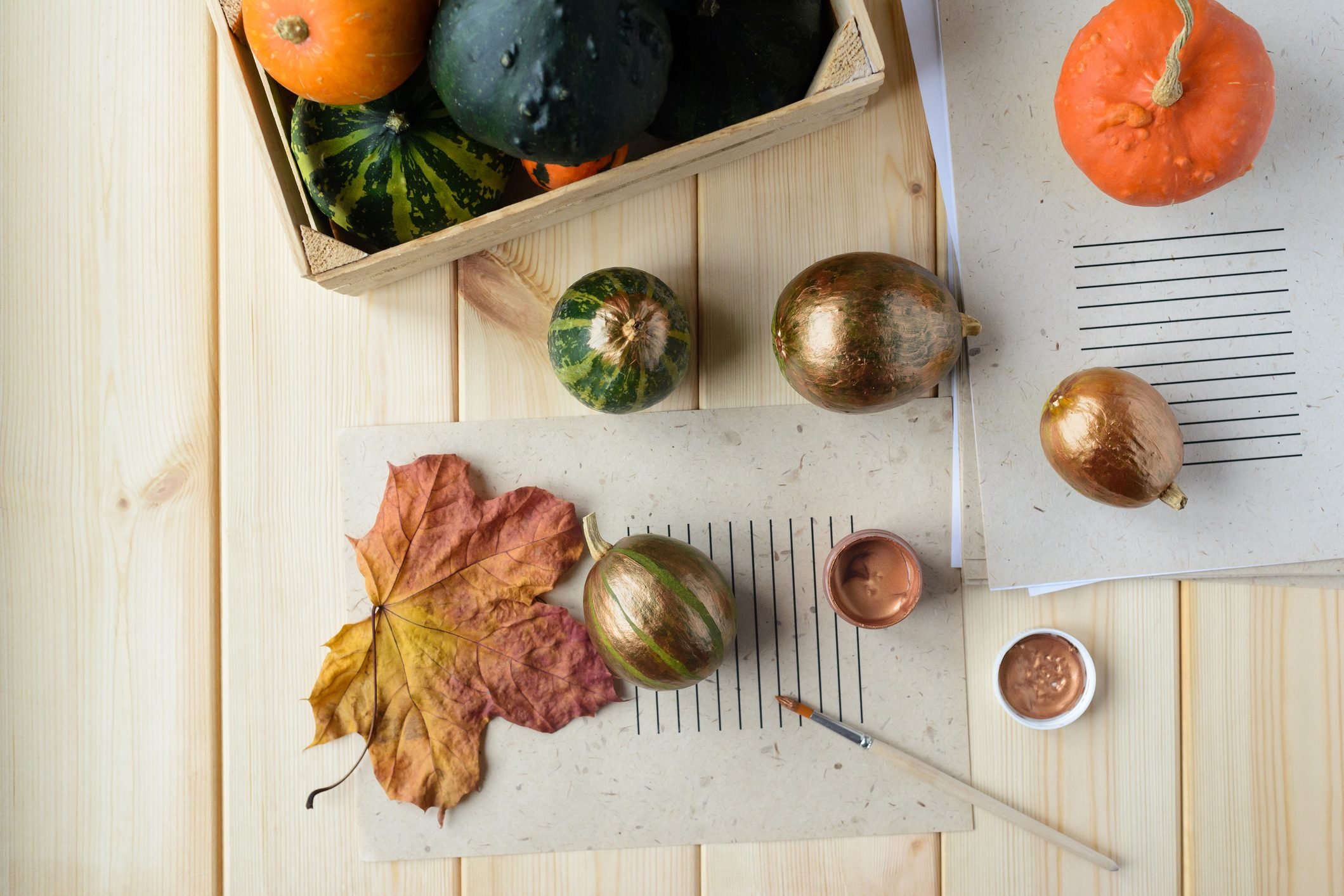 overhead view of supplies for diy autumn decor; painting pumpkins and gourds bronze on wood table background