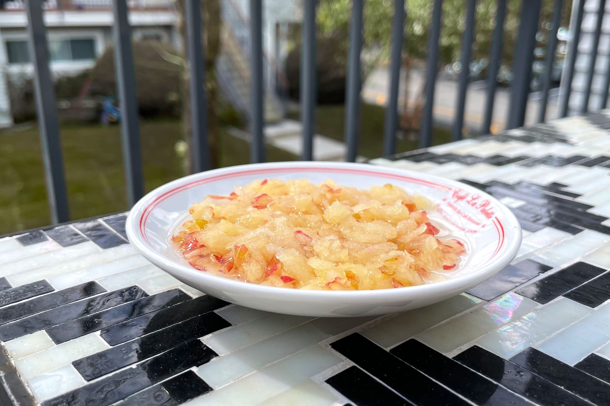 grated apples and water in a small white dish on an outdoor table for feeding bees in winter