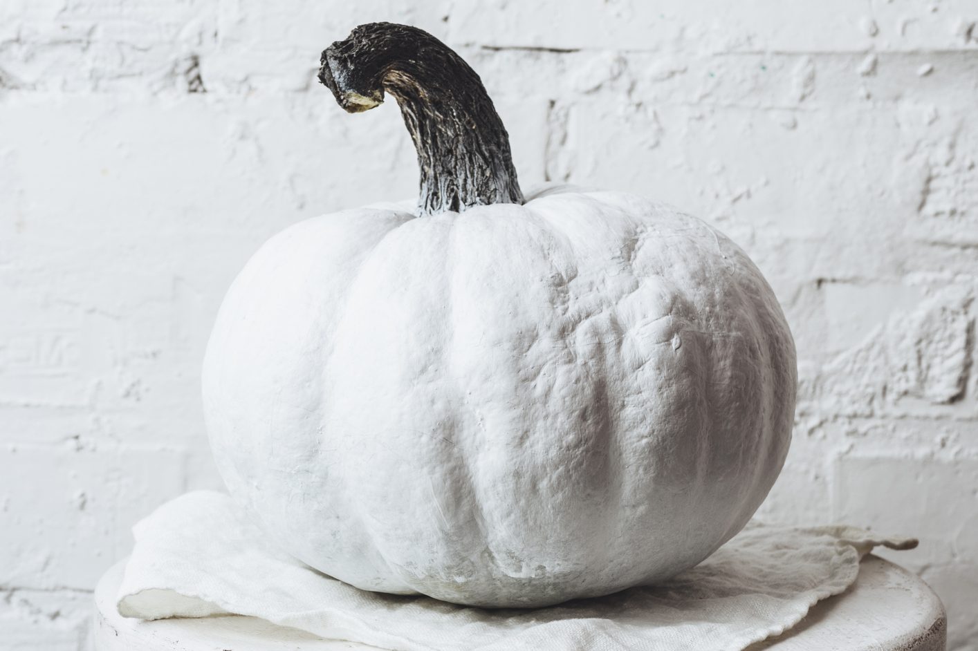 close-up shot of white painted halloween pumpkin in front of white brick wall
