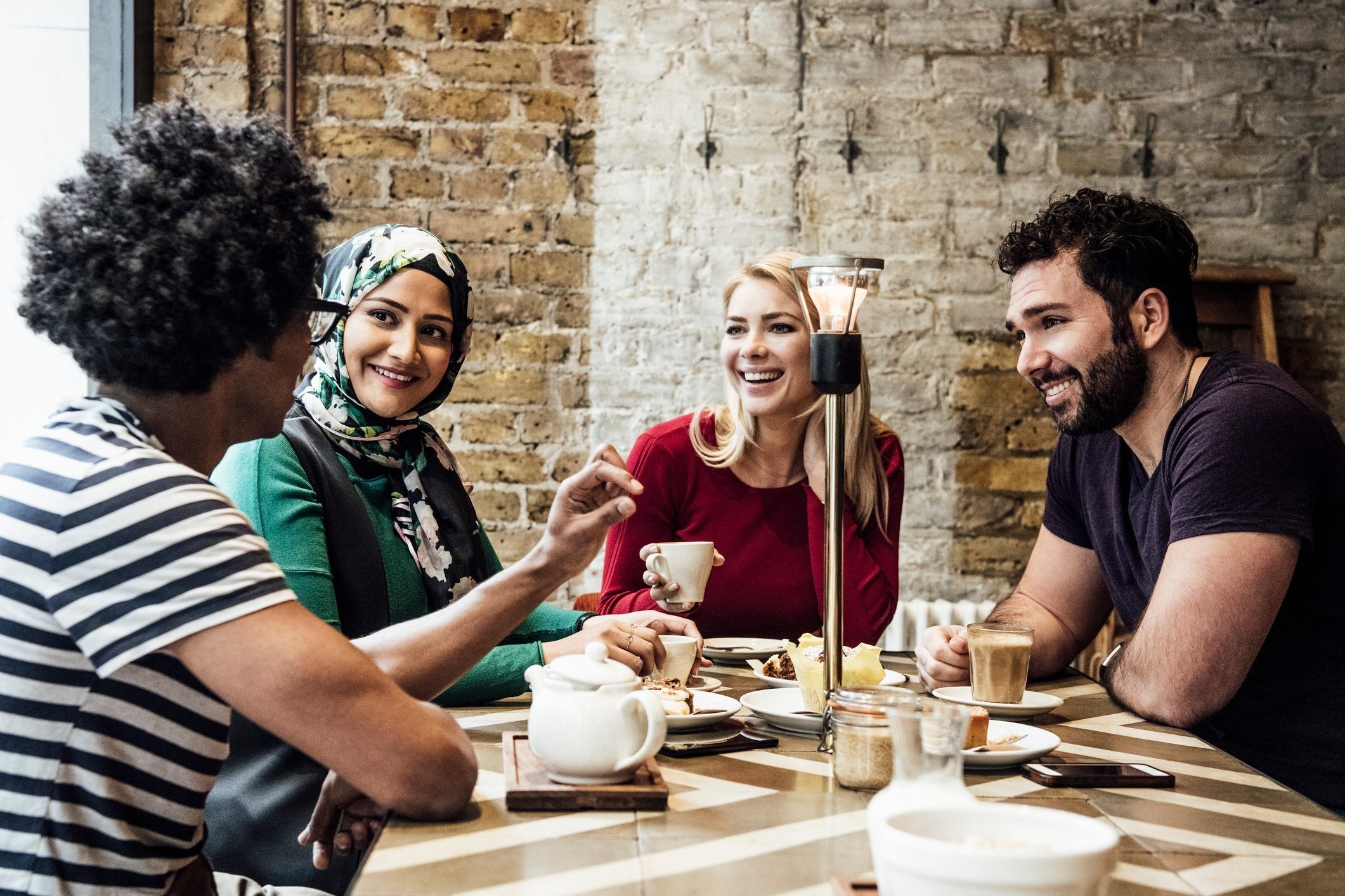 Group Of Friends Sitting In Cafe Smiling And Talking