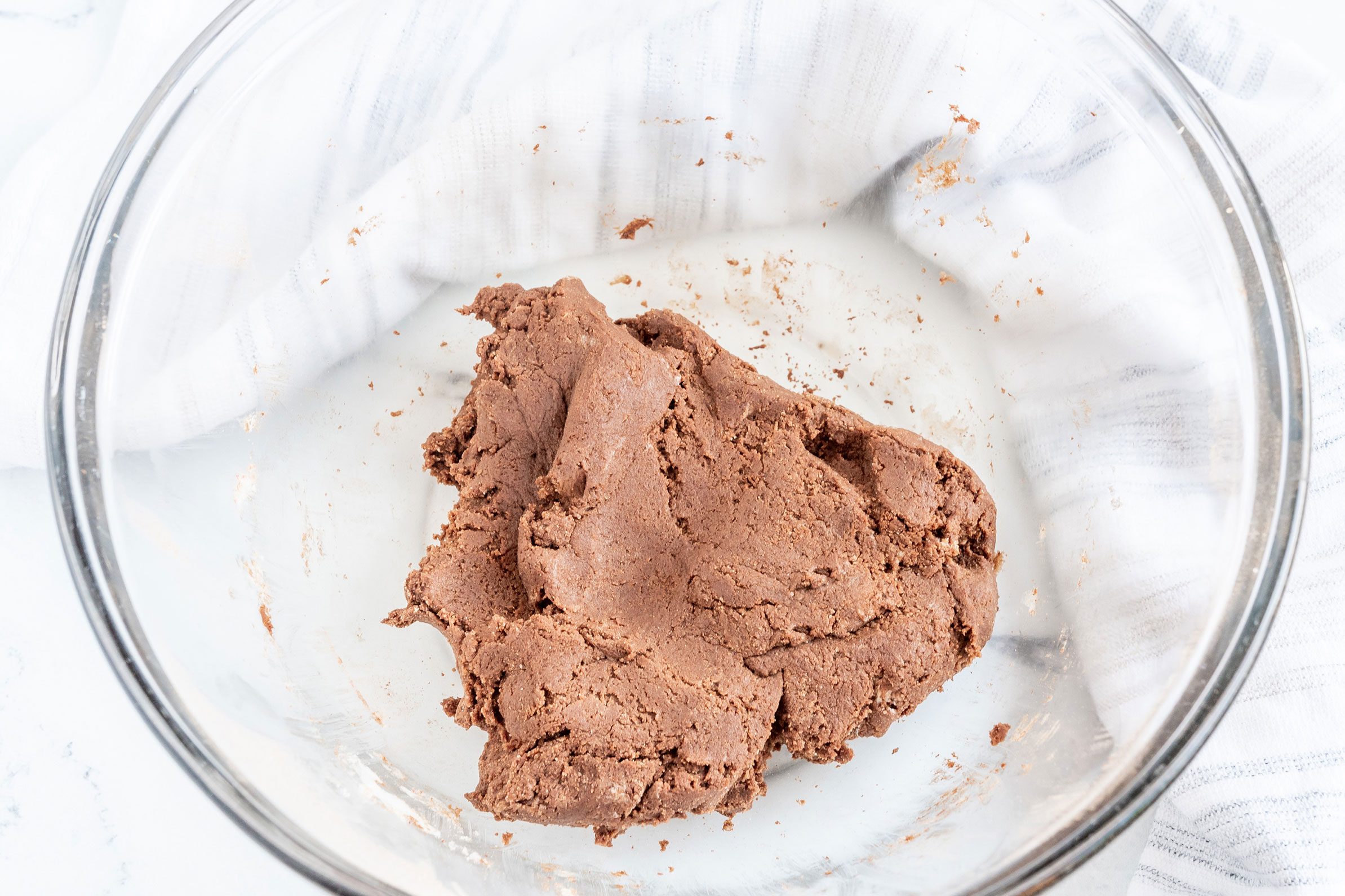 Homemade Thin Mints dough in a clear glass bowl on a marble kitchen countertop