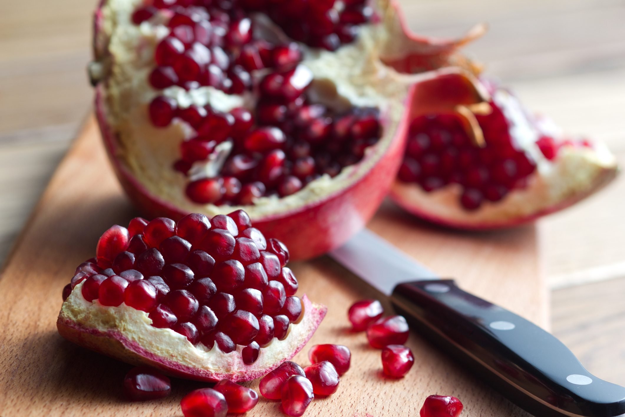 showing how to remove seeds from a pomegranate on cutting board