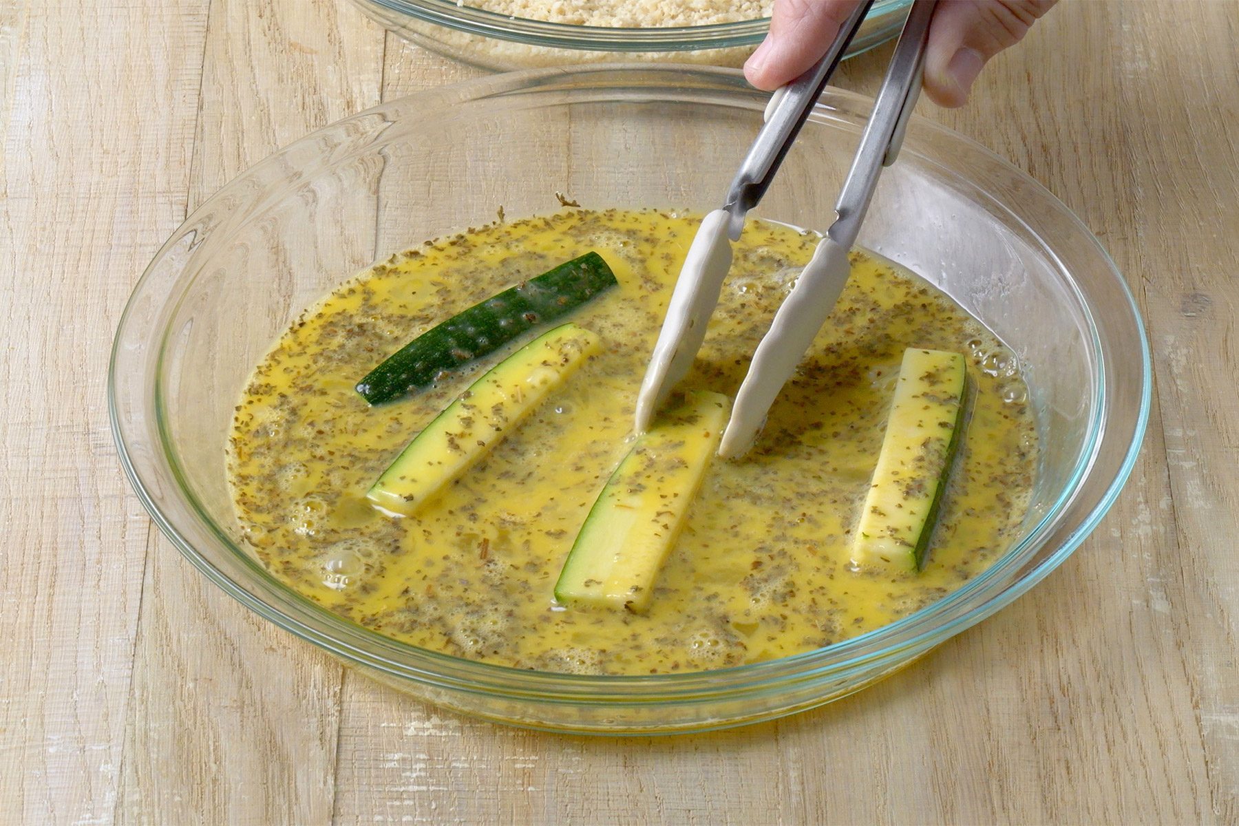 wide shot of zucchini slices dipped in egg mixture