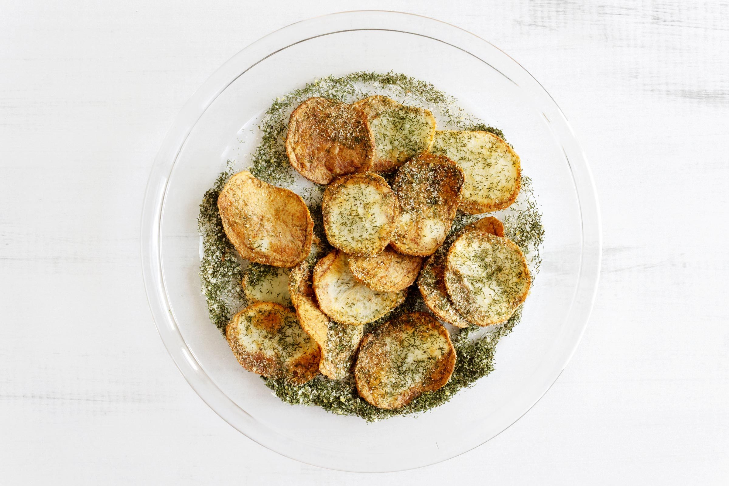 mixing fried chips in seasoning mix in a clear glass shallow bowl