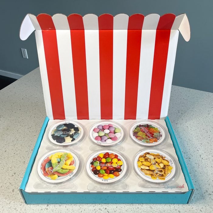 opening a sugar wish candy box to see sis small circular containers with lids labelled with pictures of the snacks and candies that are inside