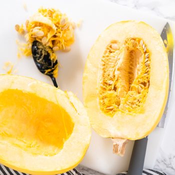 Preparing sliced open organic spaghetti squash with olive oil, salt, and pepper.