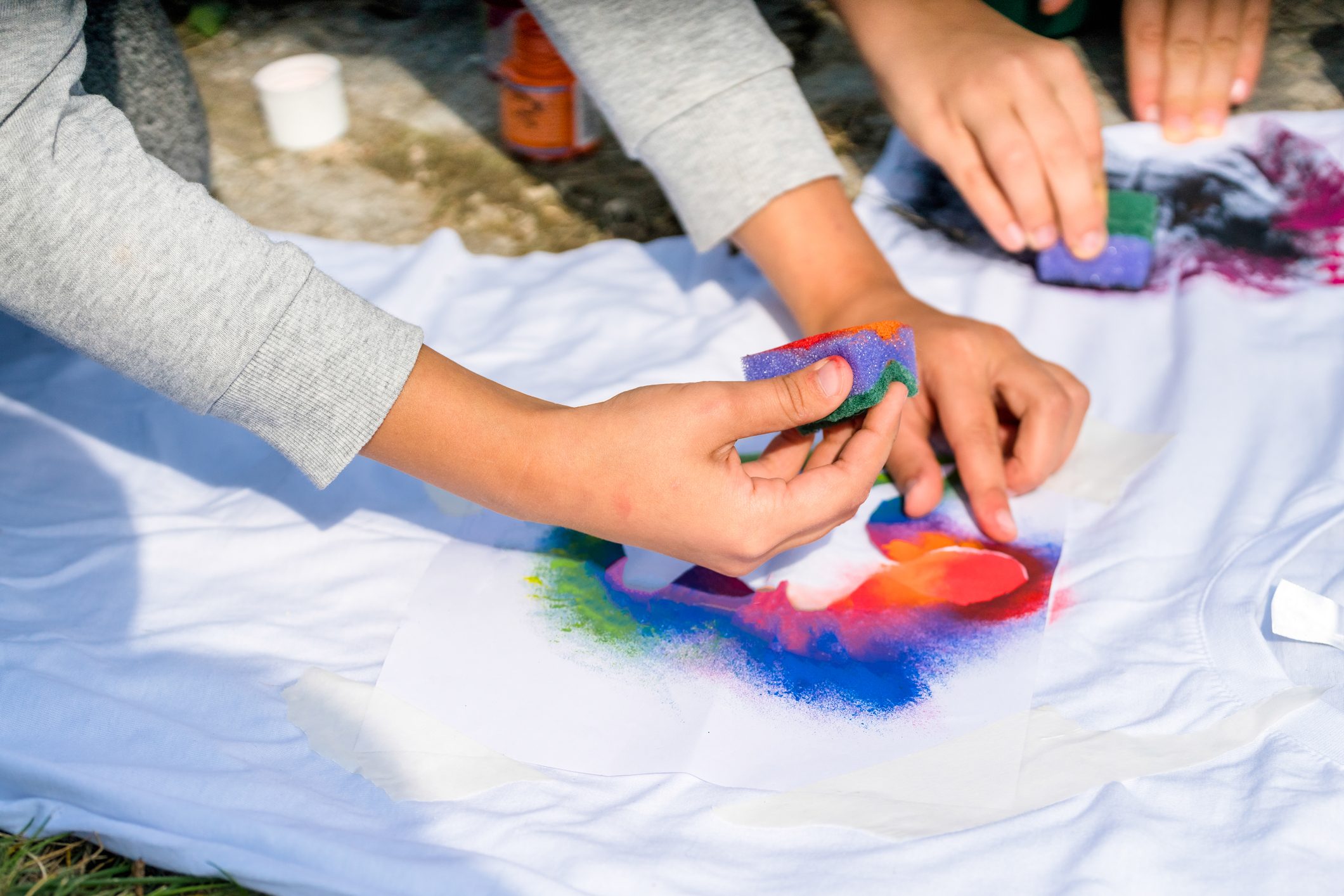 Creating your own t-shirt workshop outside. Hand applying paint on shirt