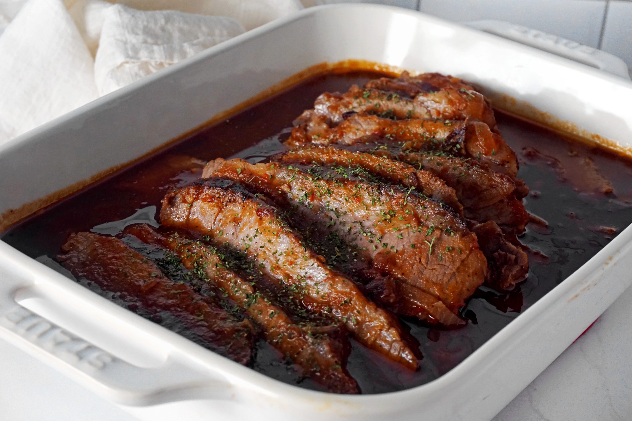 sliced brisket in a white dish for serving