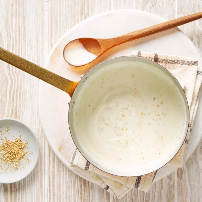 top view of white sauce in a pan with a wooden spoon to the side