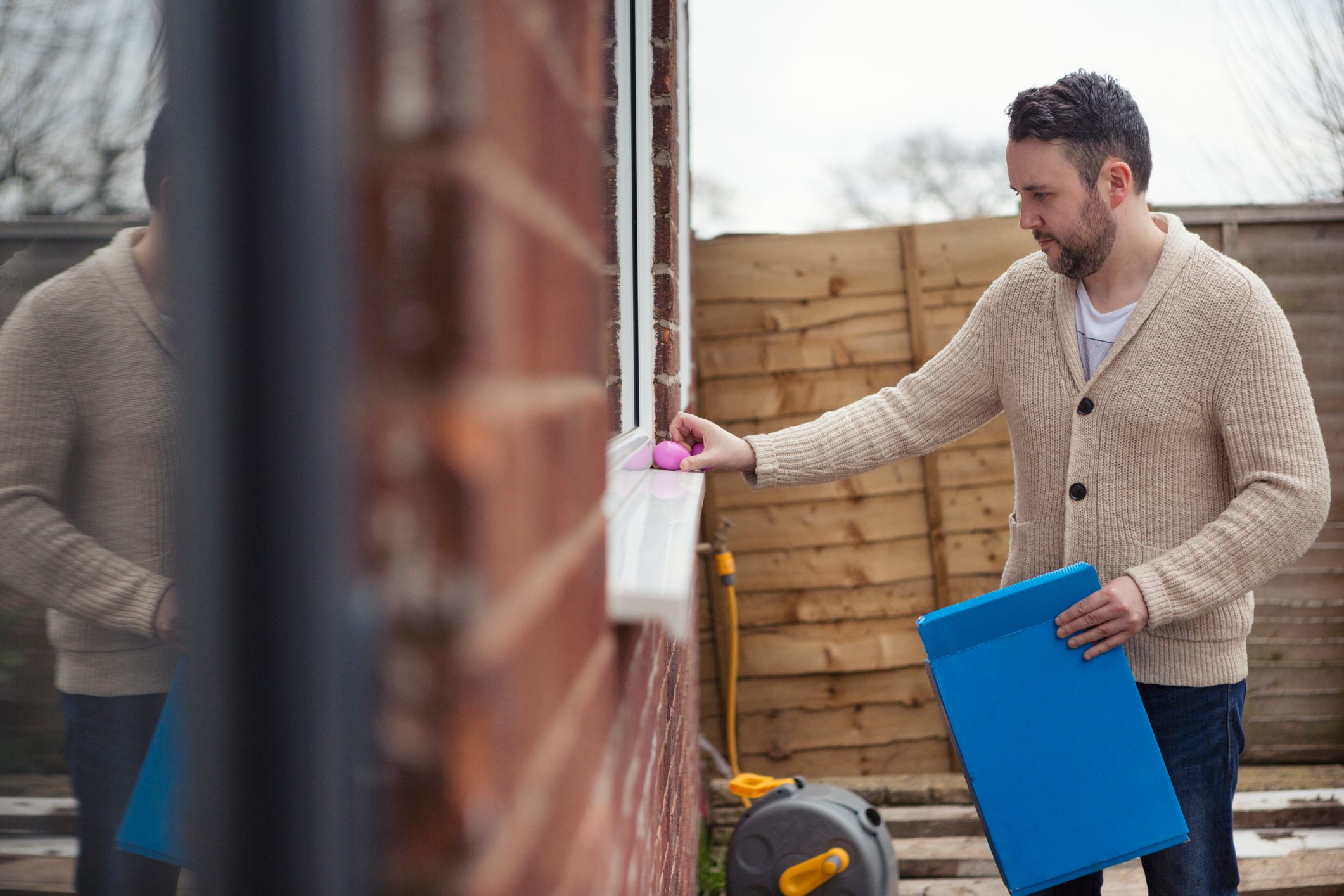 Adult male hiding Easter eggs outdoors in preparation for an Easter egg hunt