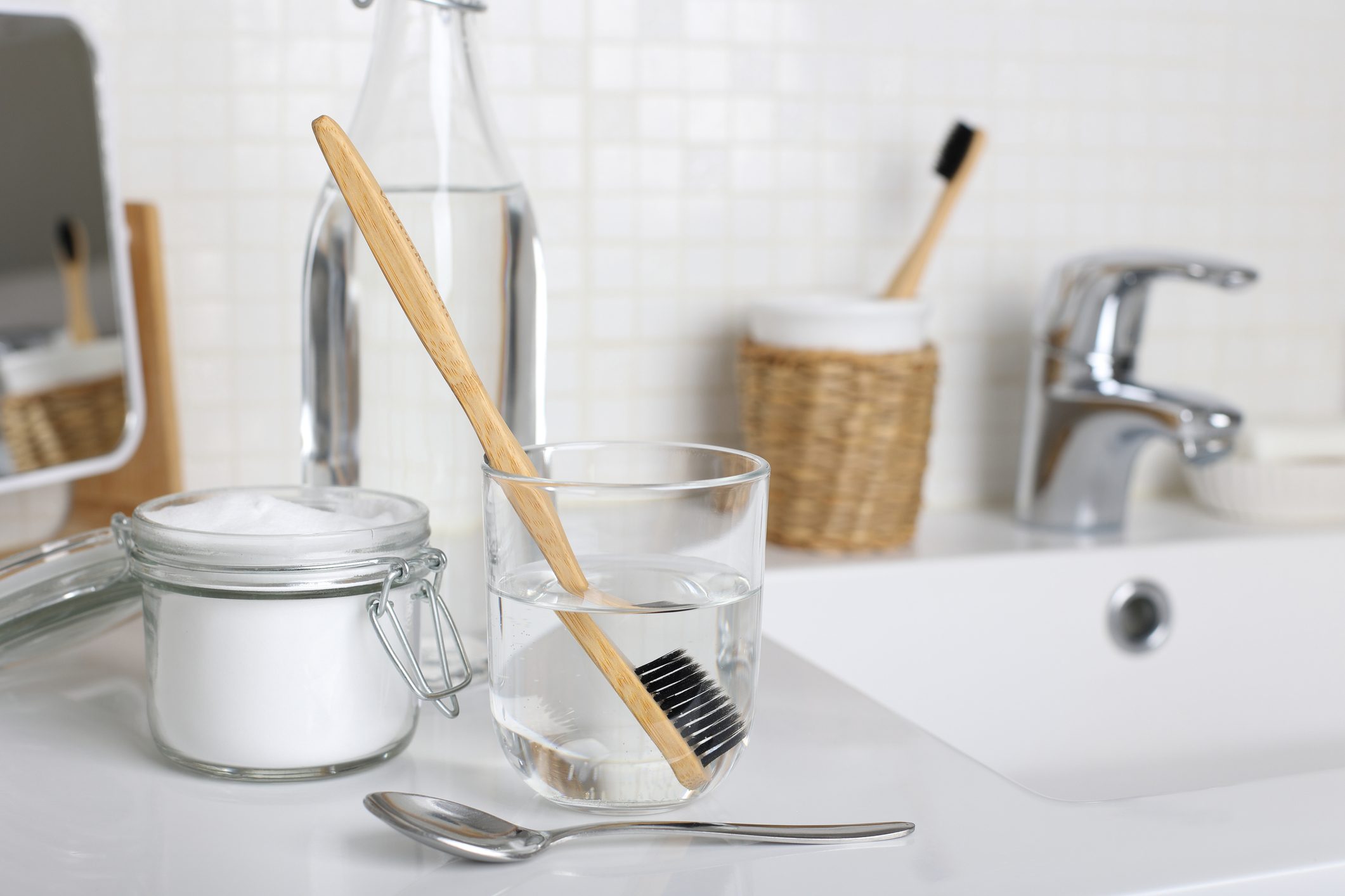 Cleaning a toothbrush with white vinegar, water and baking soda solution on the bathroom sink close up.