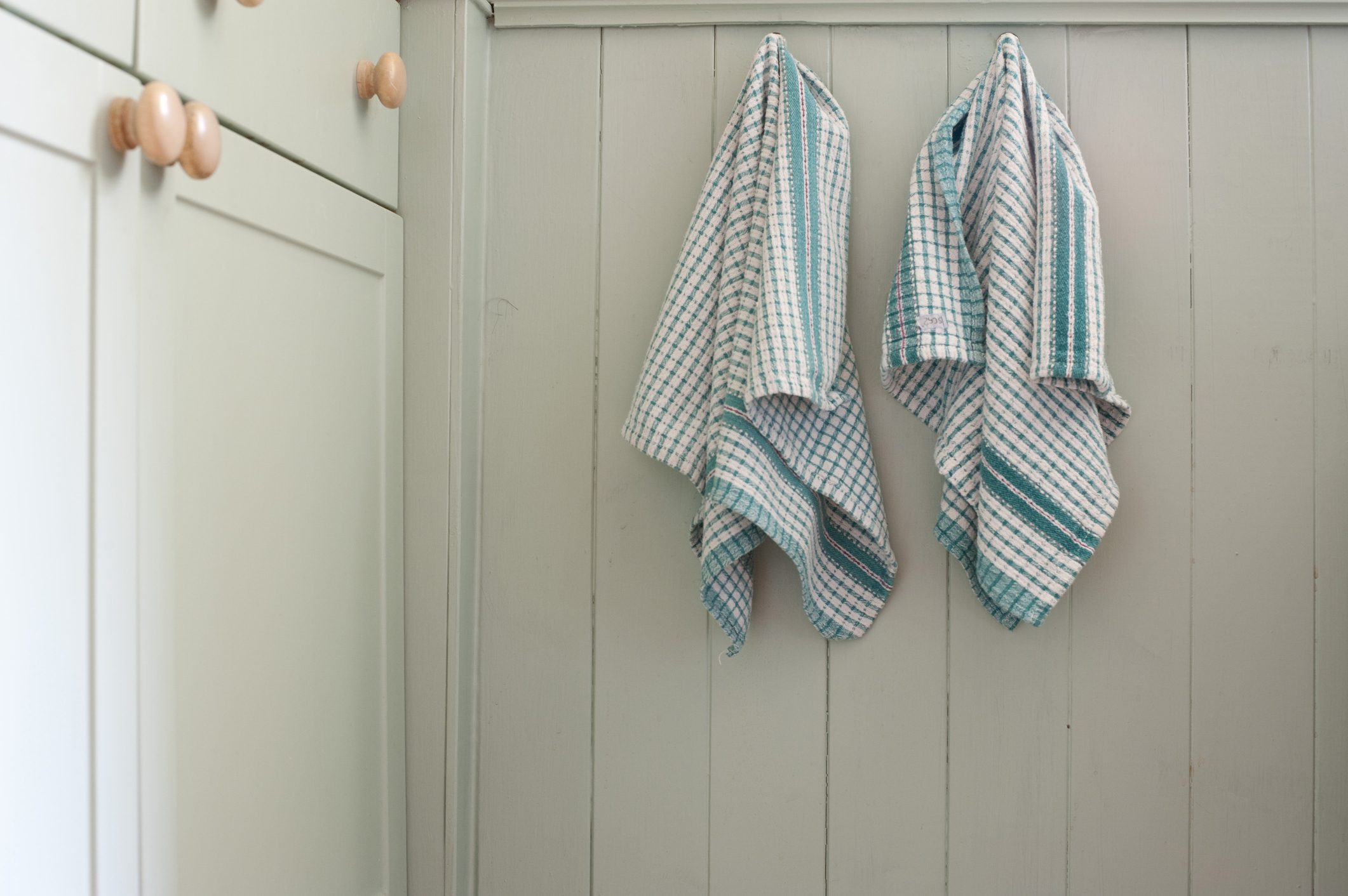 Dish Towels Hanging On Wooden Wall In Kitchen At Home
