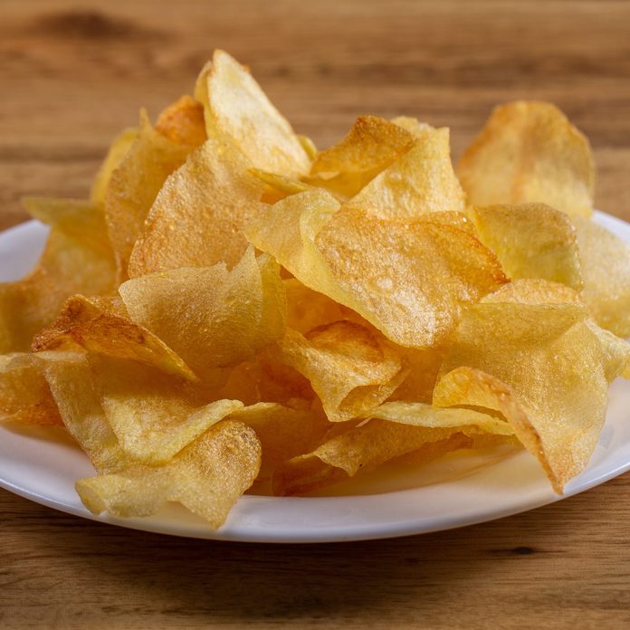 portion of potato chips on wooden background.