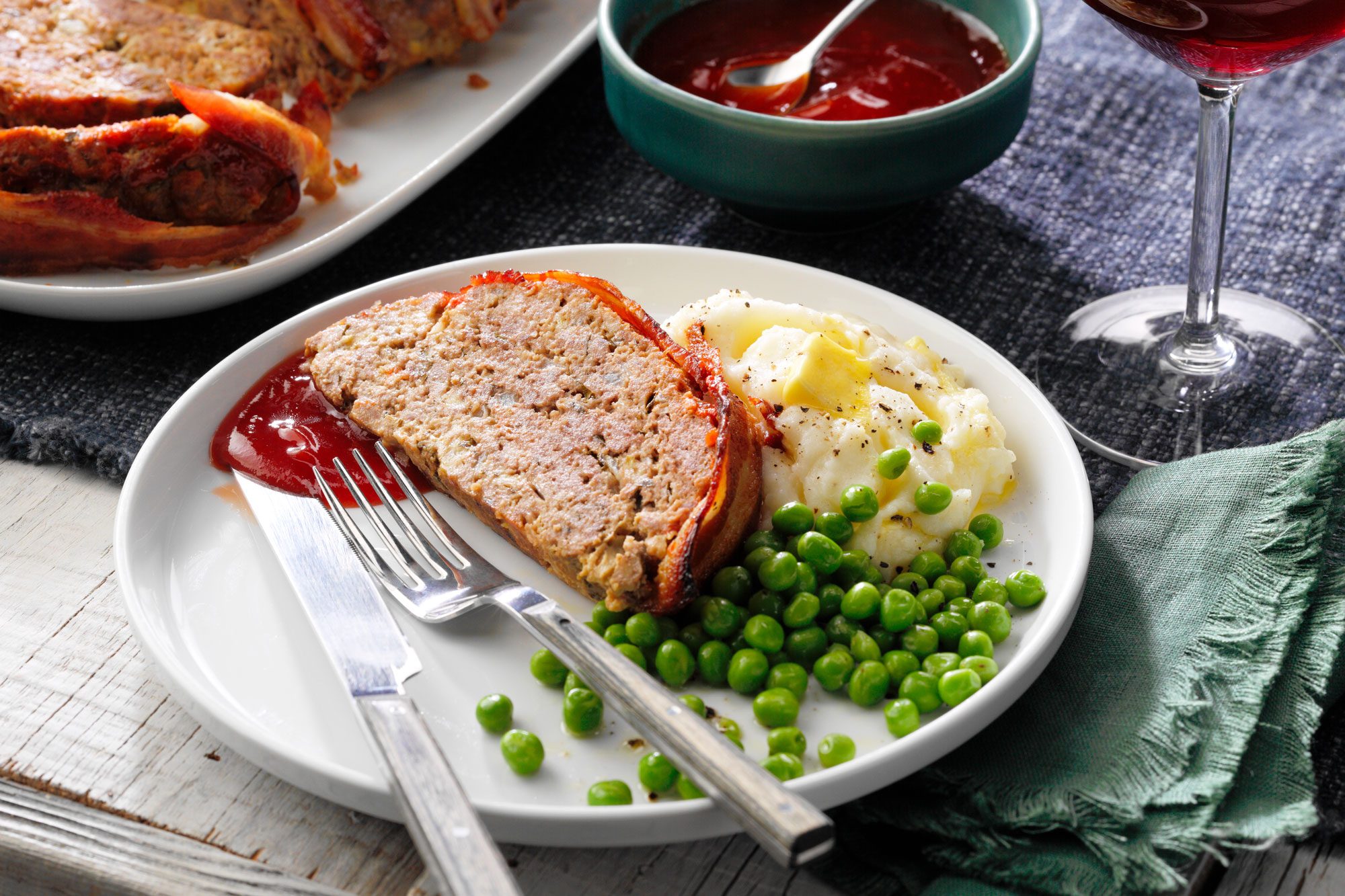 Bacon Wrapped Meat Loaf serving on a plate with sides