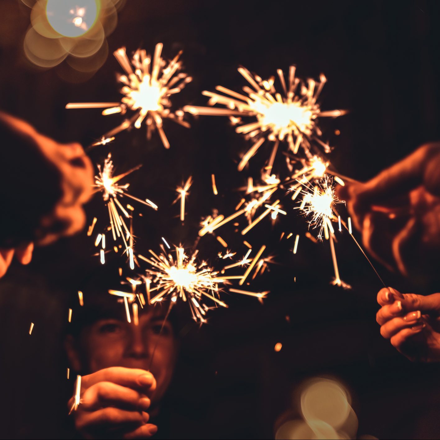 Friends celebrating Christmas and New Year together holding firework sparkles