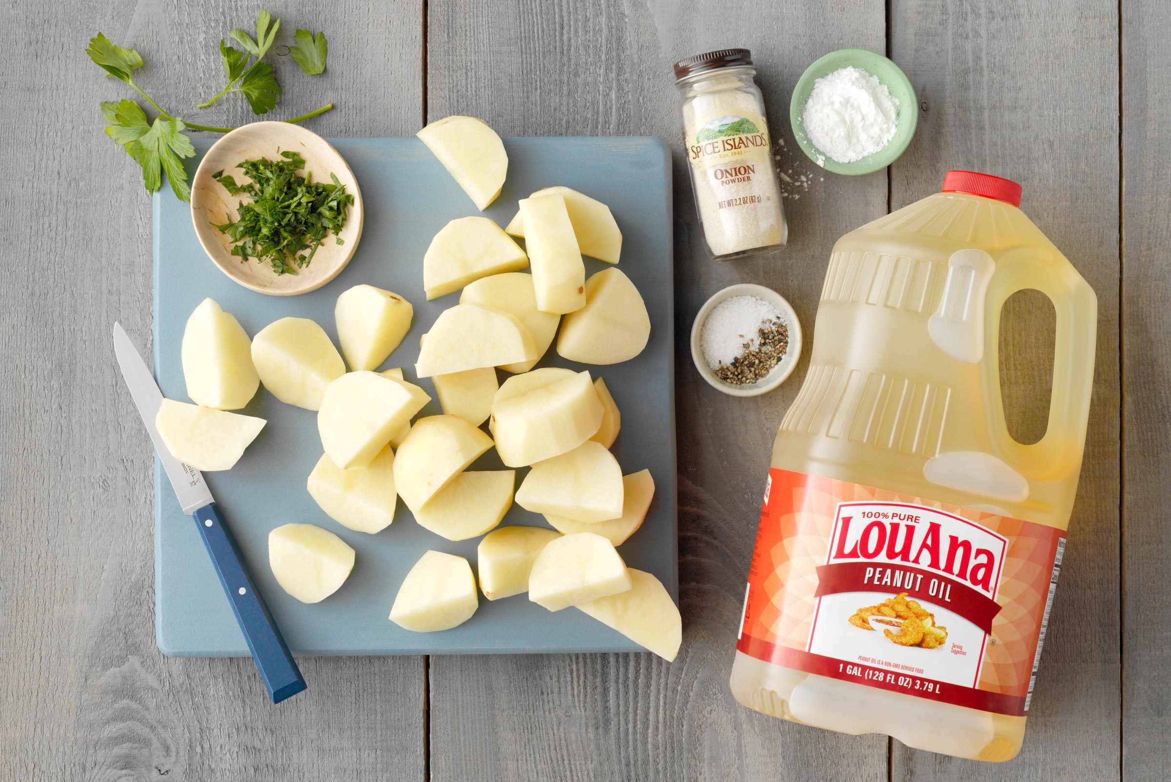 potatoes sliced on a cutting board with a bottle of peanut oil to the side