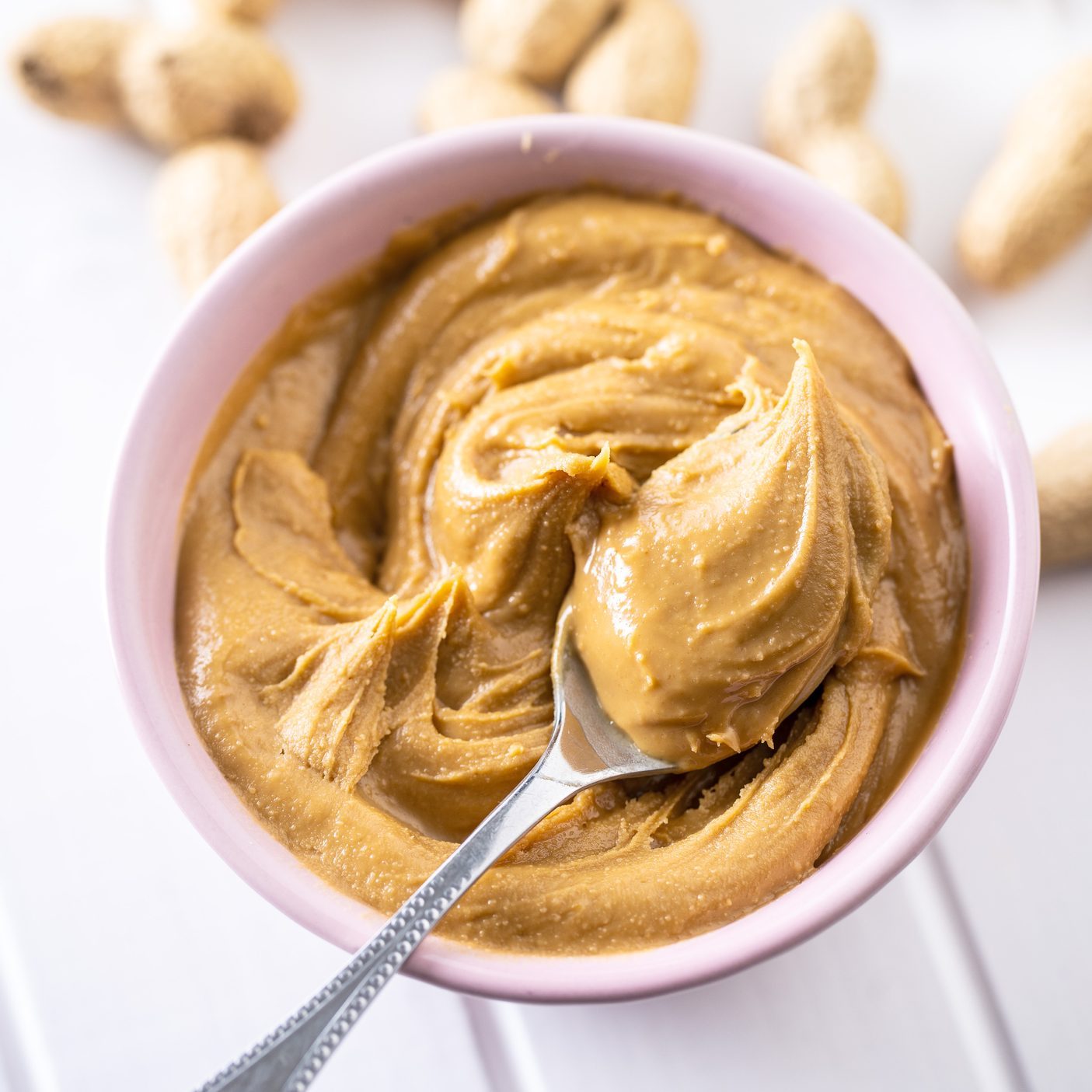 Peanut butter in bowl and peanuts
