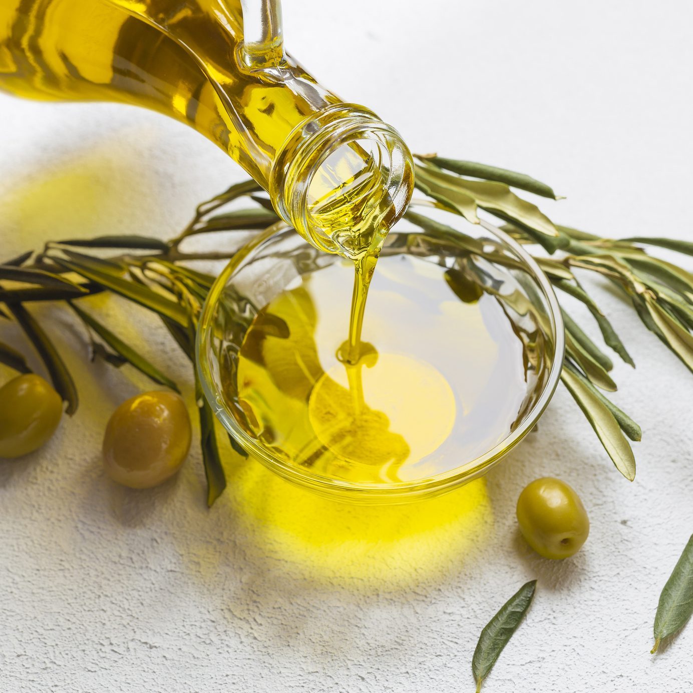 High angle view of olive oil pouring in bowl on table