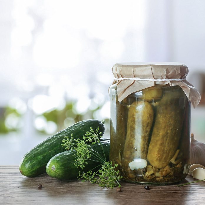 Jar With Pickled Cucumbers On Wooden Table In Kitchen