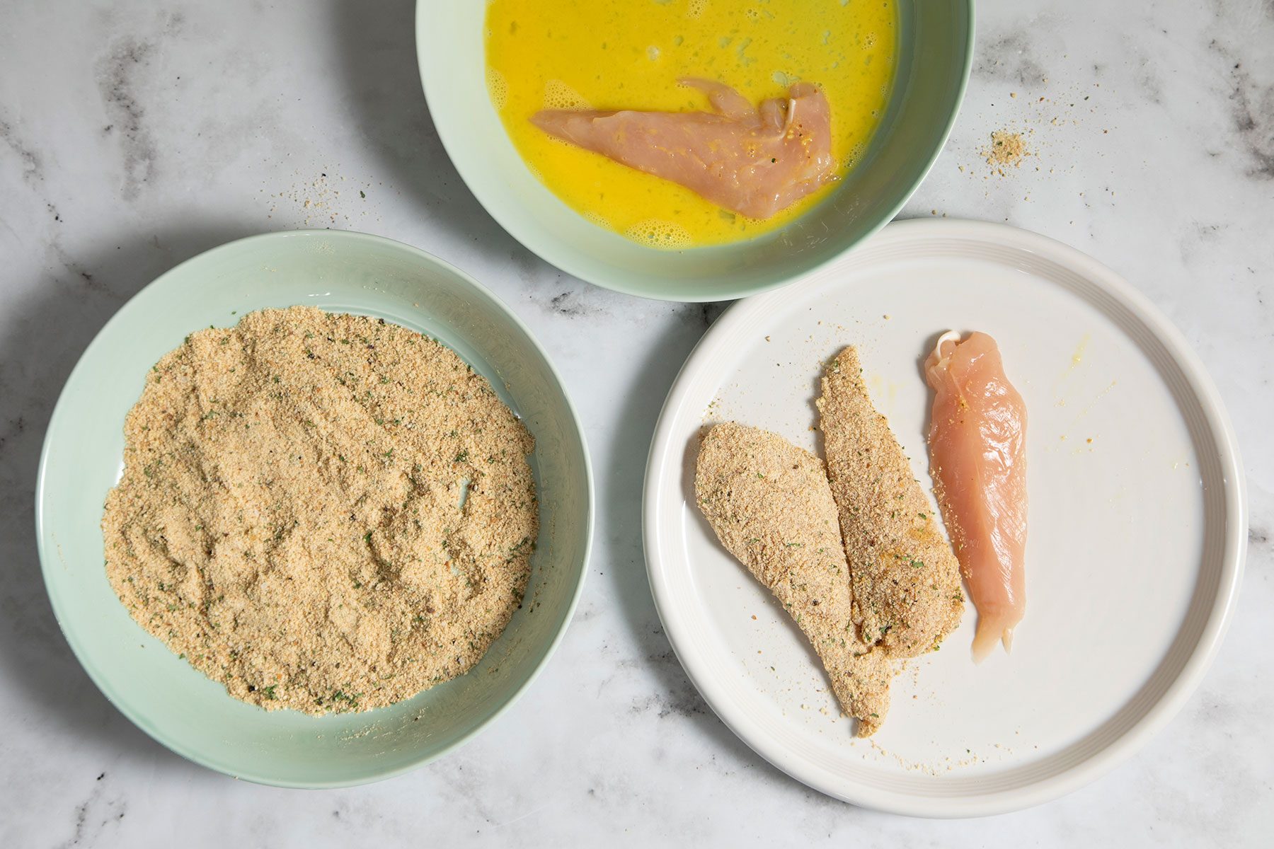 Putting chicken breast in beaten eggs and bread crumbs