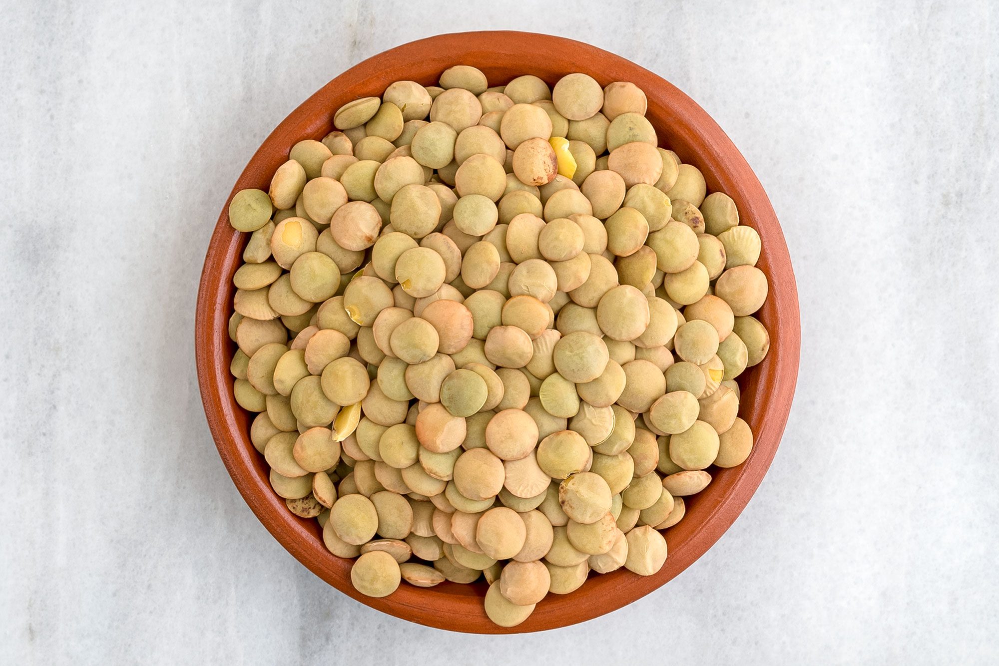 Top View Of Organic Green Lentils In A Small Bowl On A Marble Counter Top