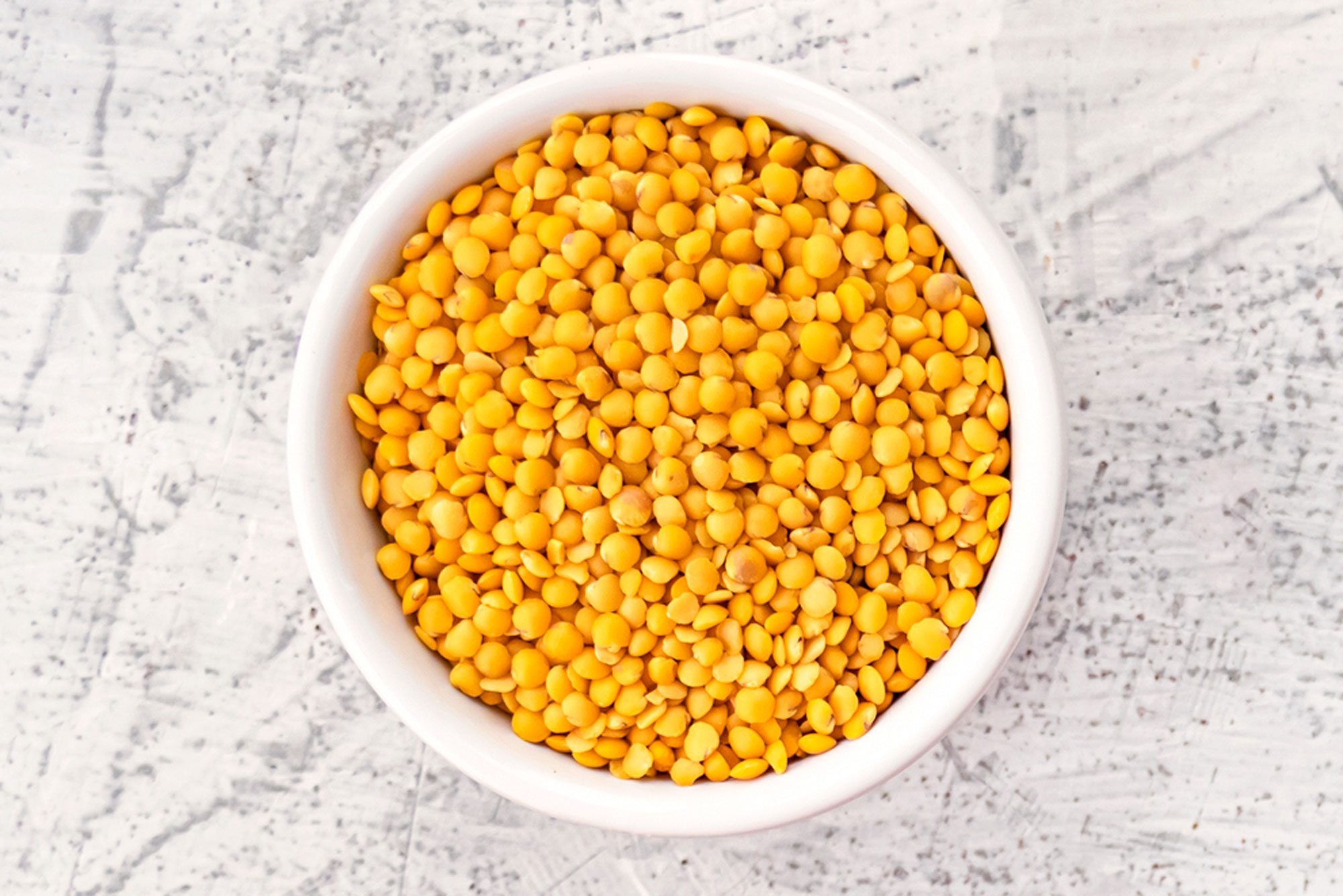 Yellow Lentils In White Bowl On White Stone Background