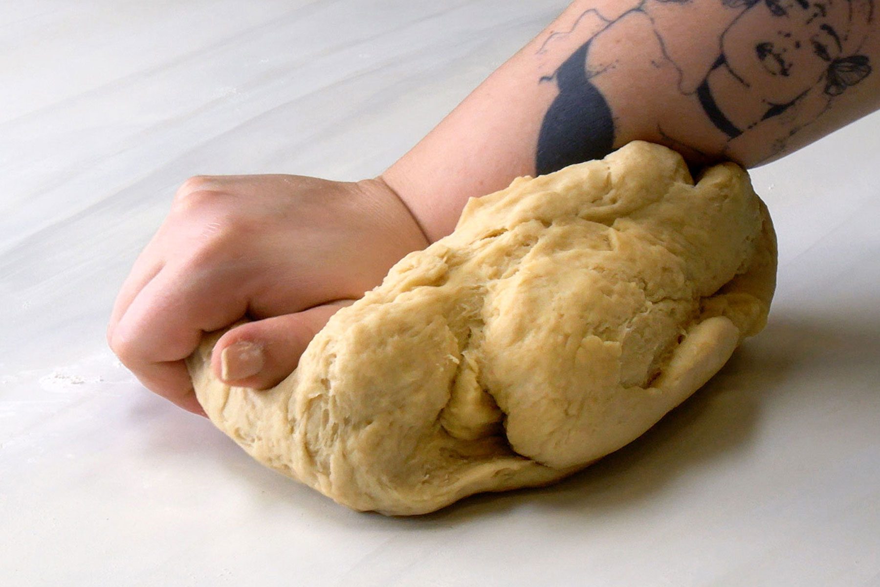 A person Kneading the dough on a marble surface