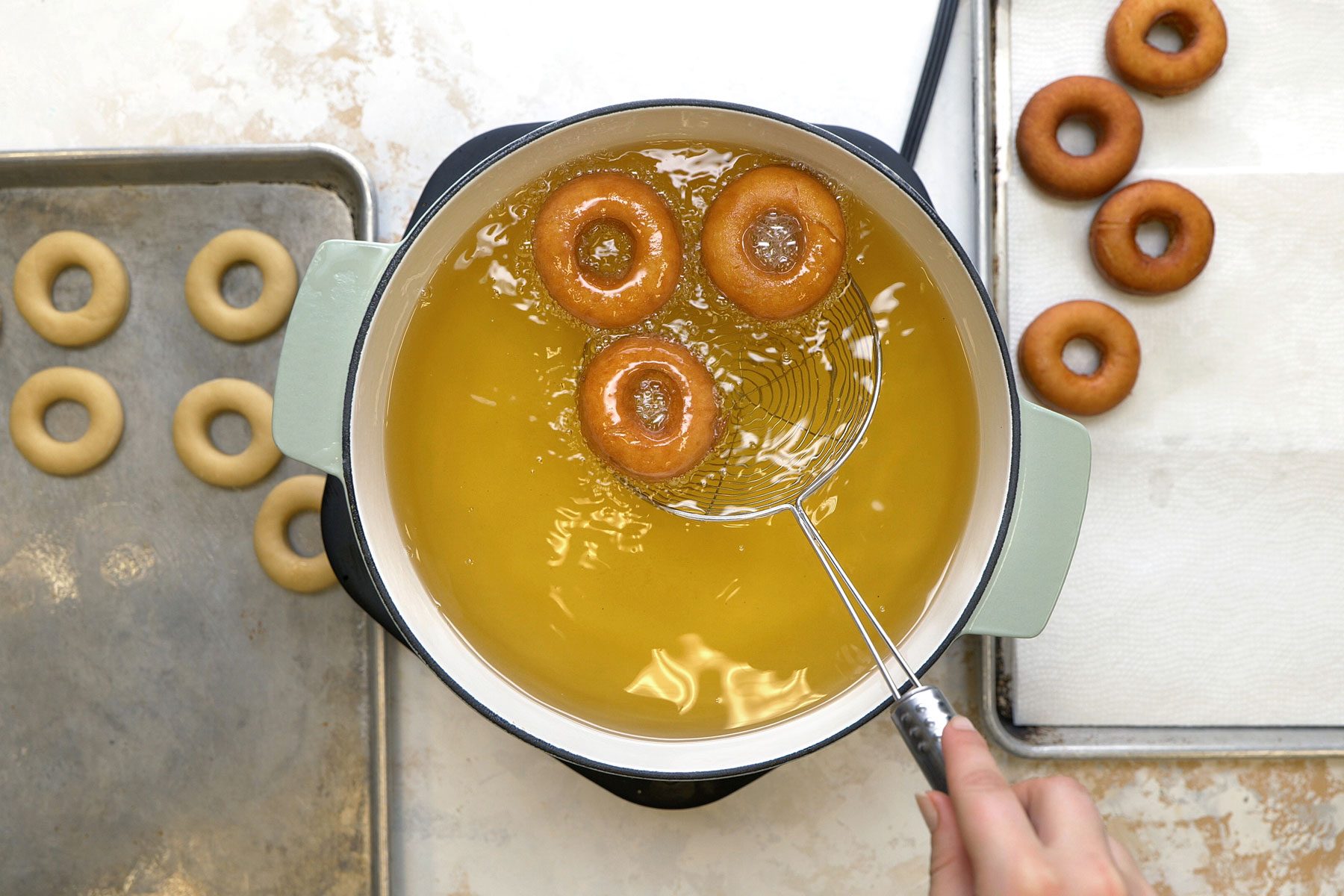 Frying the doughnuts in oil inside a large pan