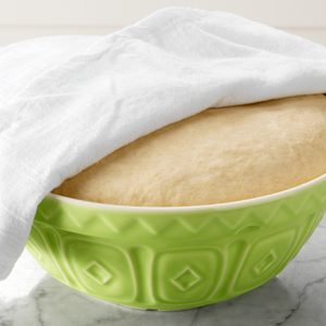 proofing bread dough in a bowl with towel covering the bowl