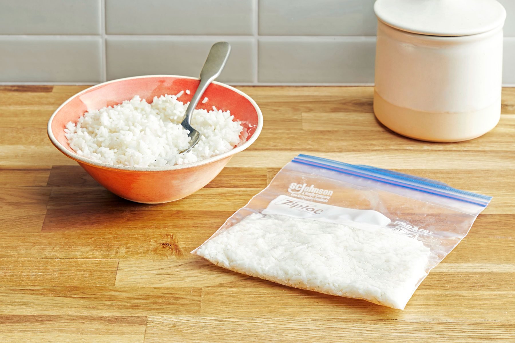 Bowl of cooked white rice next to bag of frozen rice on a kitchen counter