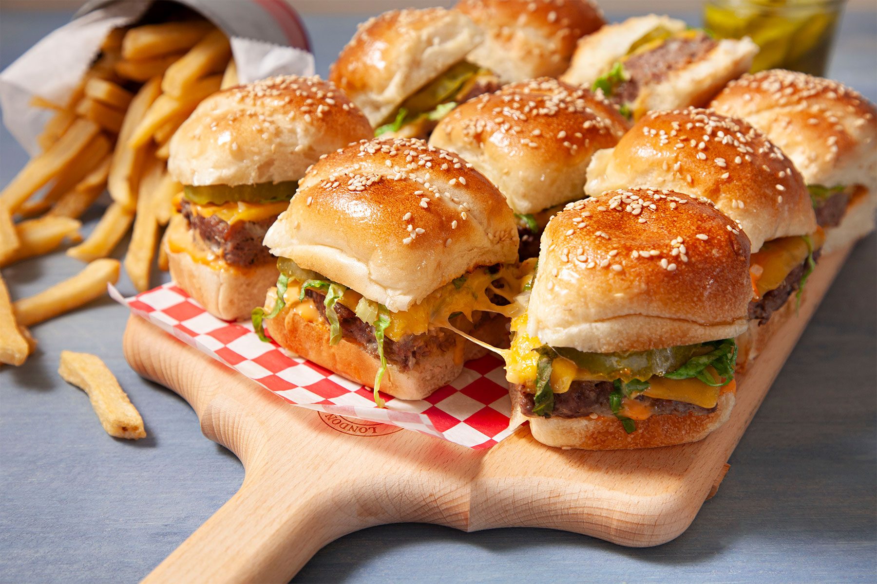 close shot of burger sliders on wooden plank