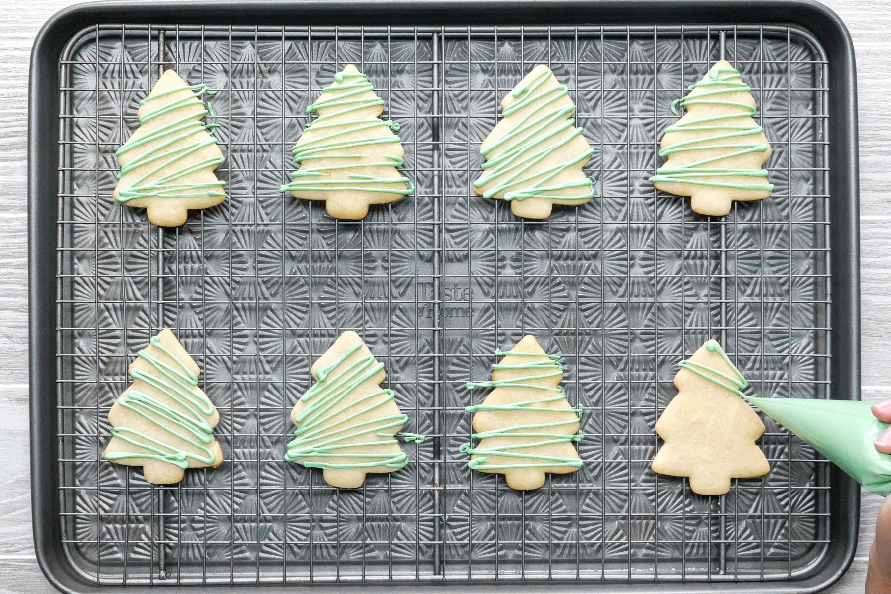 Decorating Christmas Sugar Cookies with food coloring on a cooling tray 