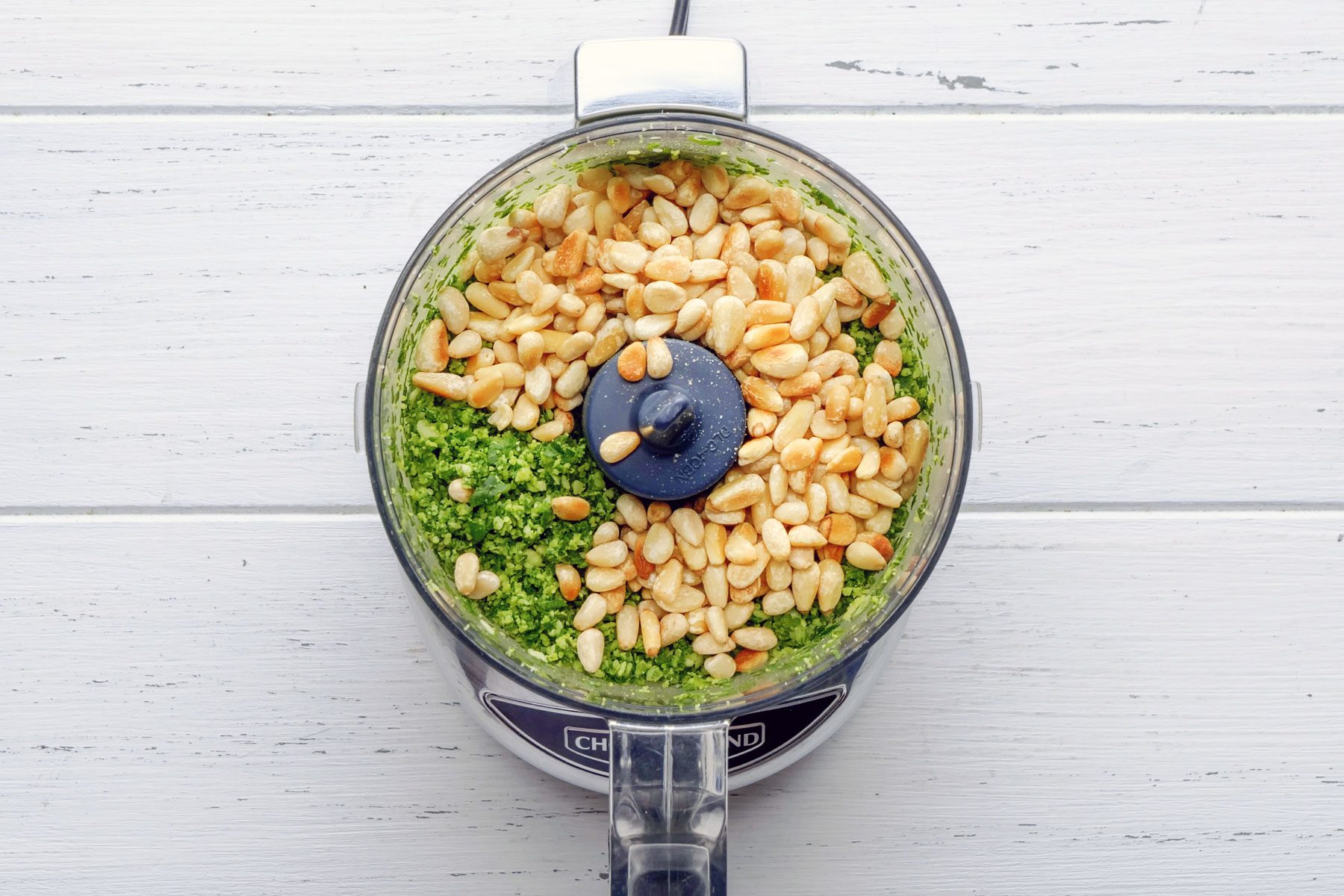 Pine nuts mixed with basil leaves mixture in a blender