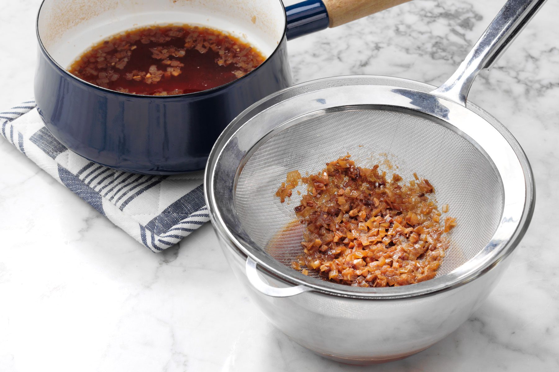 A pot with a lid and a strainer next to it.