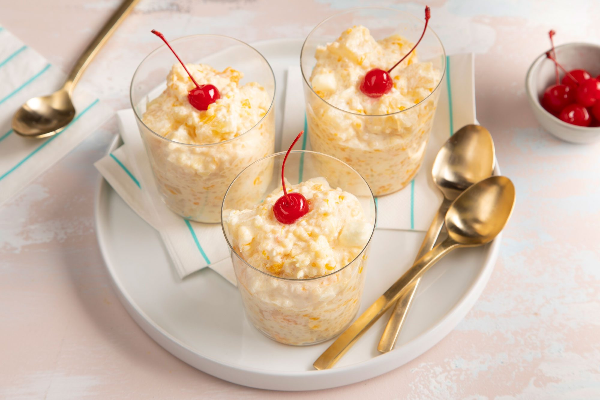 Frog Eye Salad Served in dessert cups garnished with cherries; golden spoons; a small bowl of cherries;