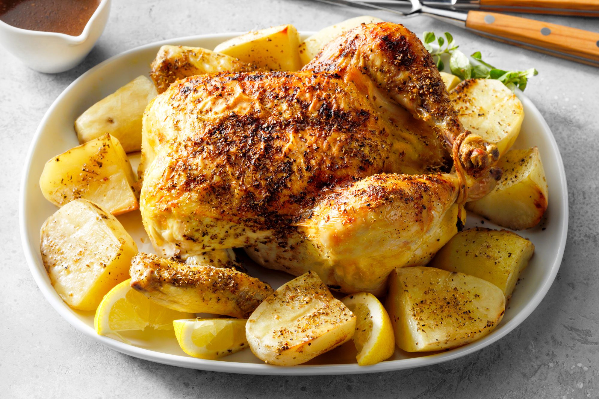 Greek Chicken And Potatoes Served on an oval shaped plate on marble surface