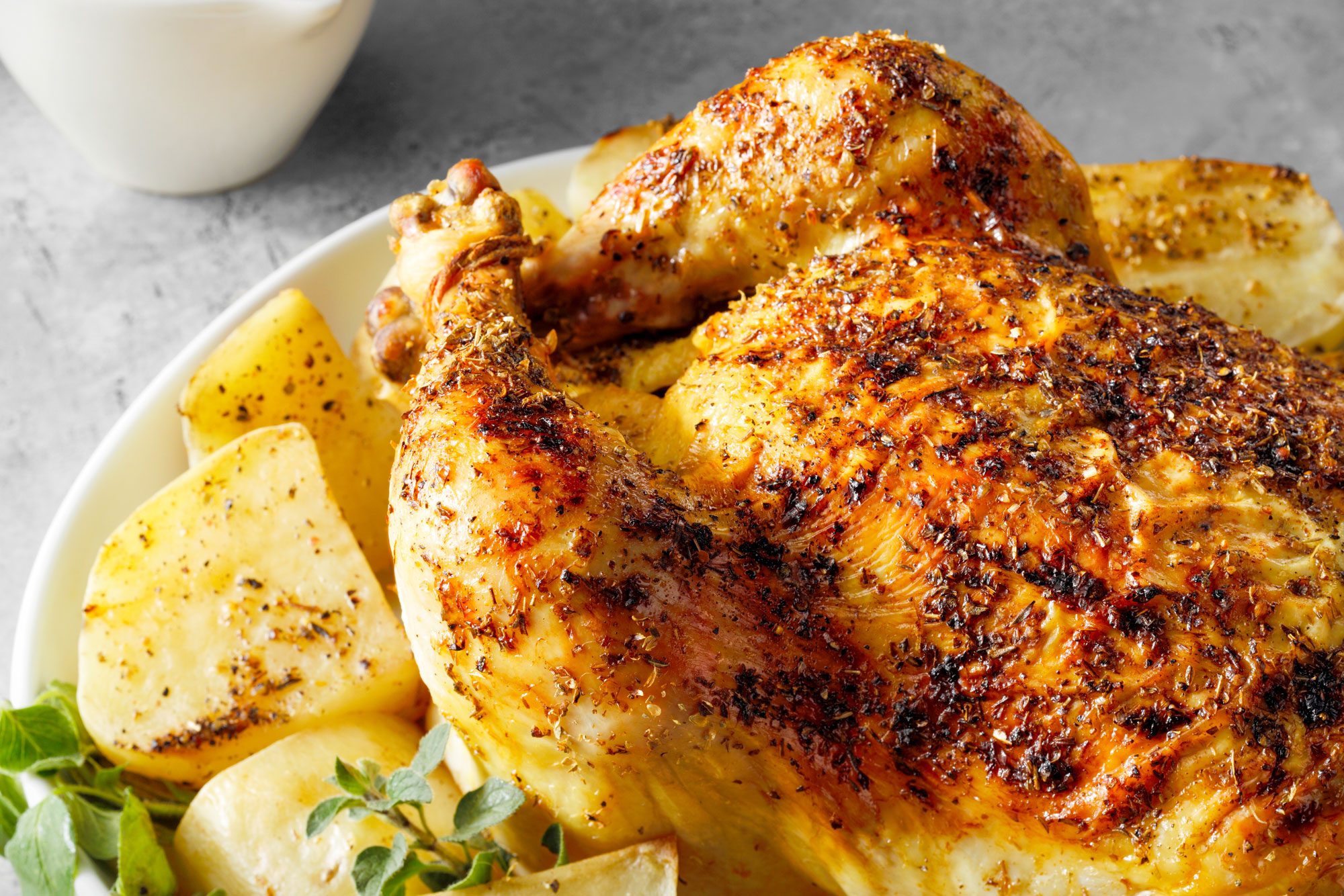 Greek Chicken And Potatoes Served on an oval shaped plate on marble surface