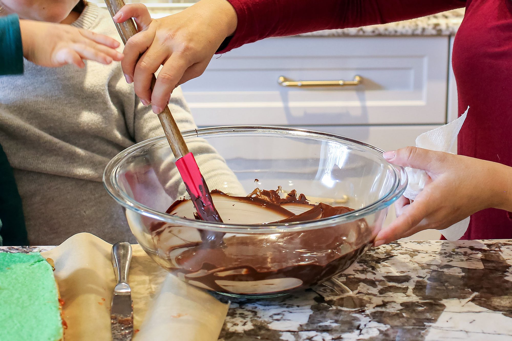 A Person Mixing Chocolate Glaze in a Large Glass Bowl
