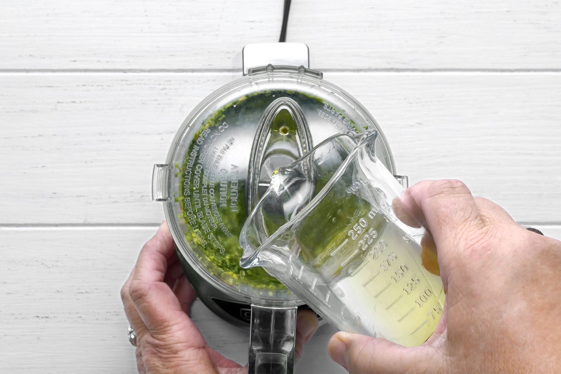 Overhead shot of gradually adding oil in a steady stream; white wooden background;