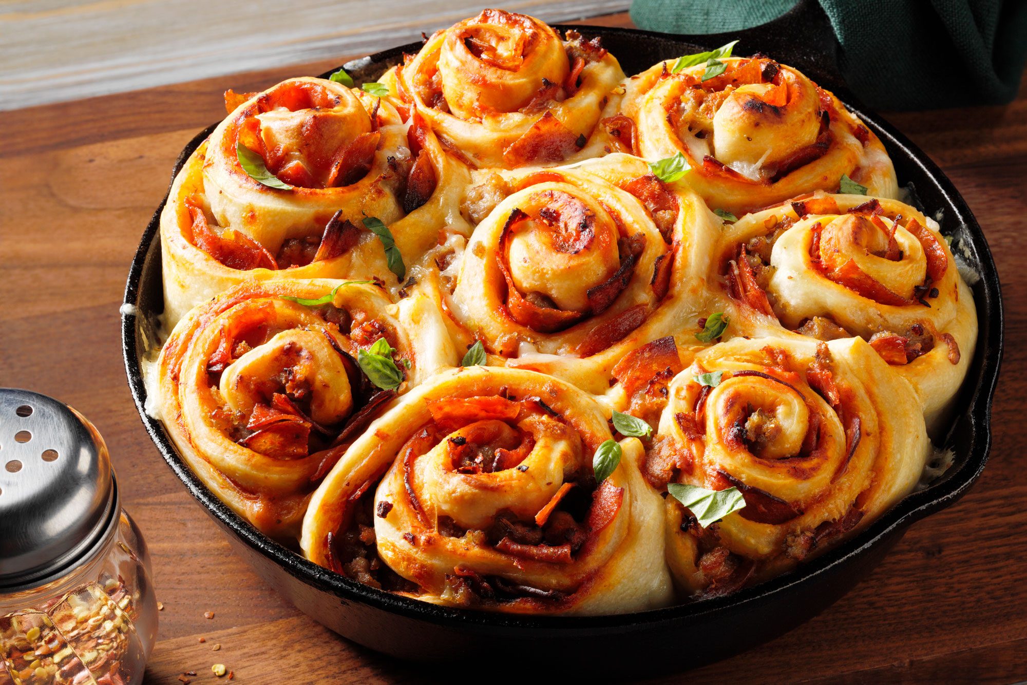 A bowl filled with delicious Cheesy Pizza Rolls sprinkled with pepper flakes