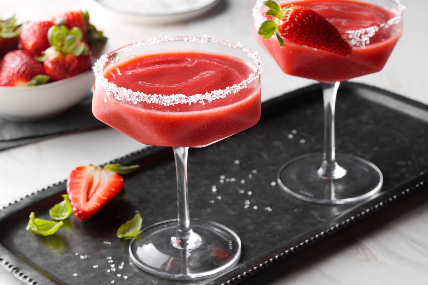 Strawberry Margarita served on black tray with strawberries and mint leaves