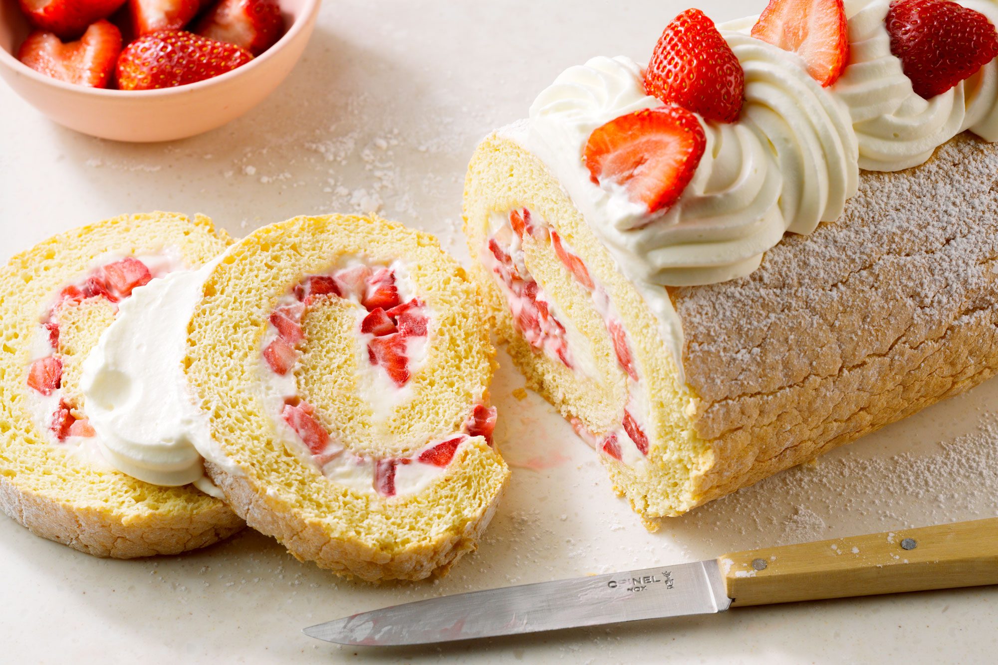 3/4th shot; horizontal shot; white textured background; Strawberry Cream Cake Roll placed on white board;