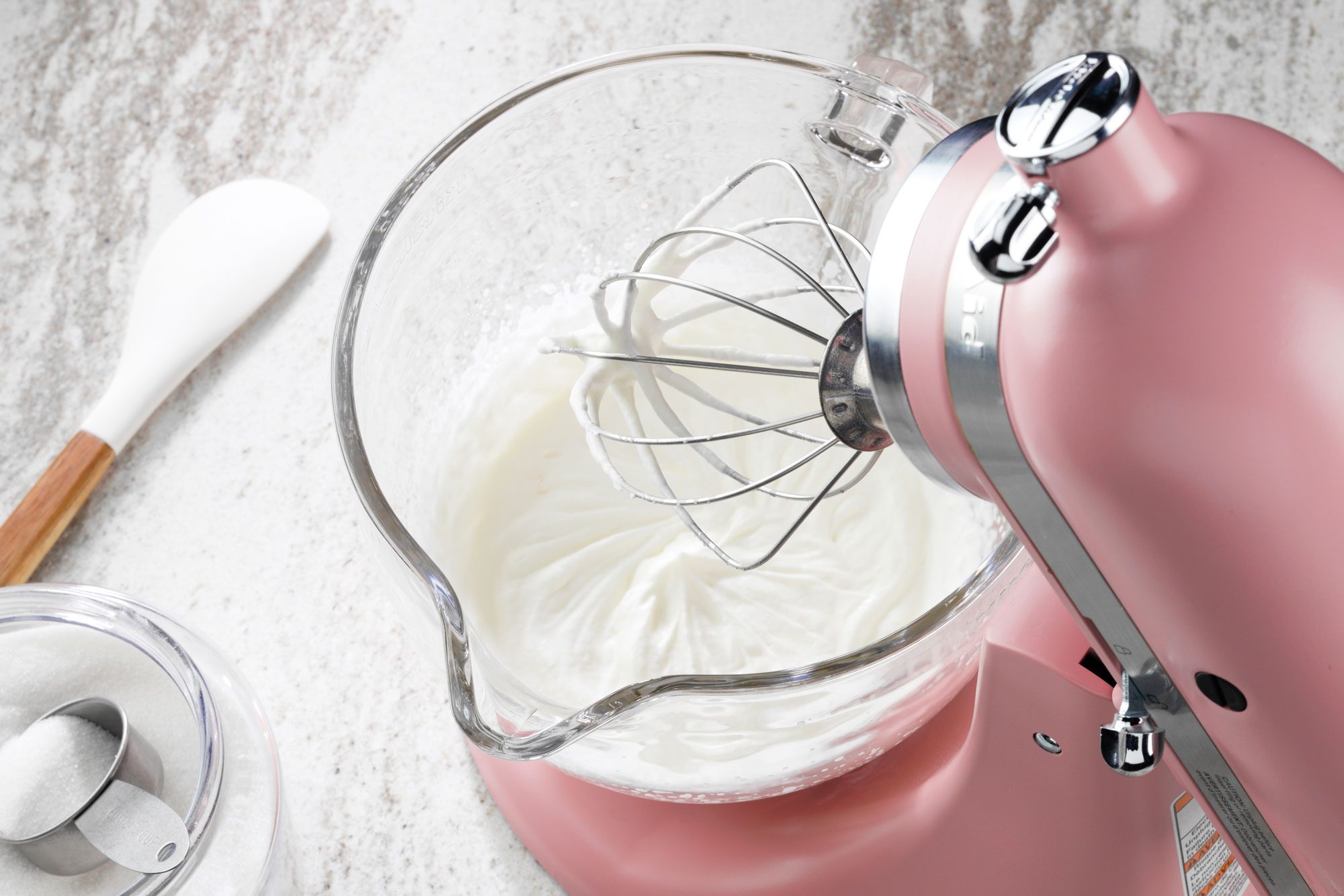 tilted shot; white textured background; Whipping cream sugar and vanilla with electric whisker;