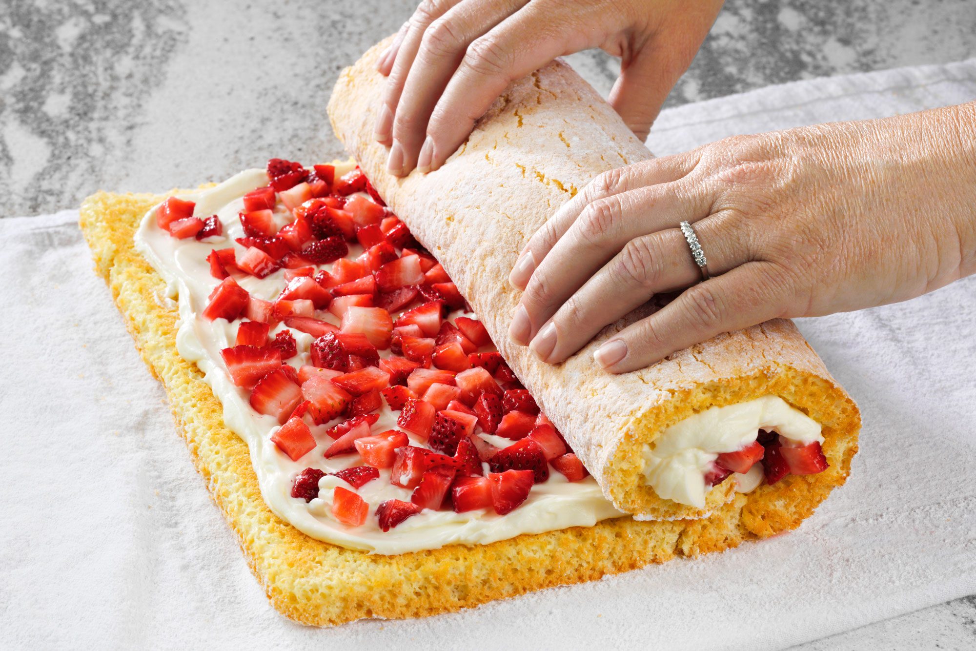 3/4th shot; white textured background; Re rolling Strawberry-Roll cake;