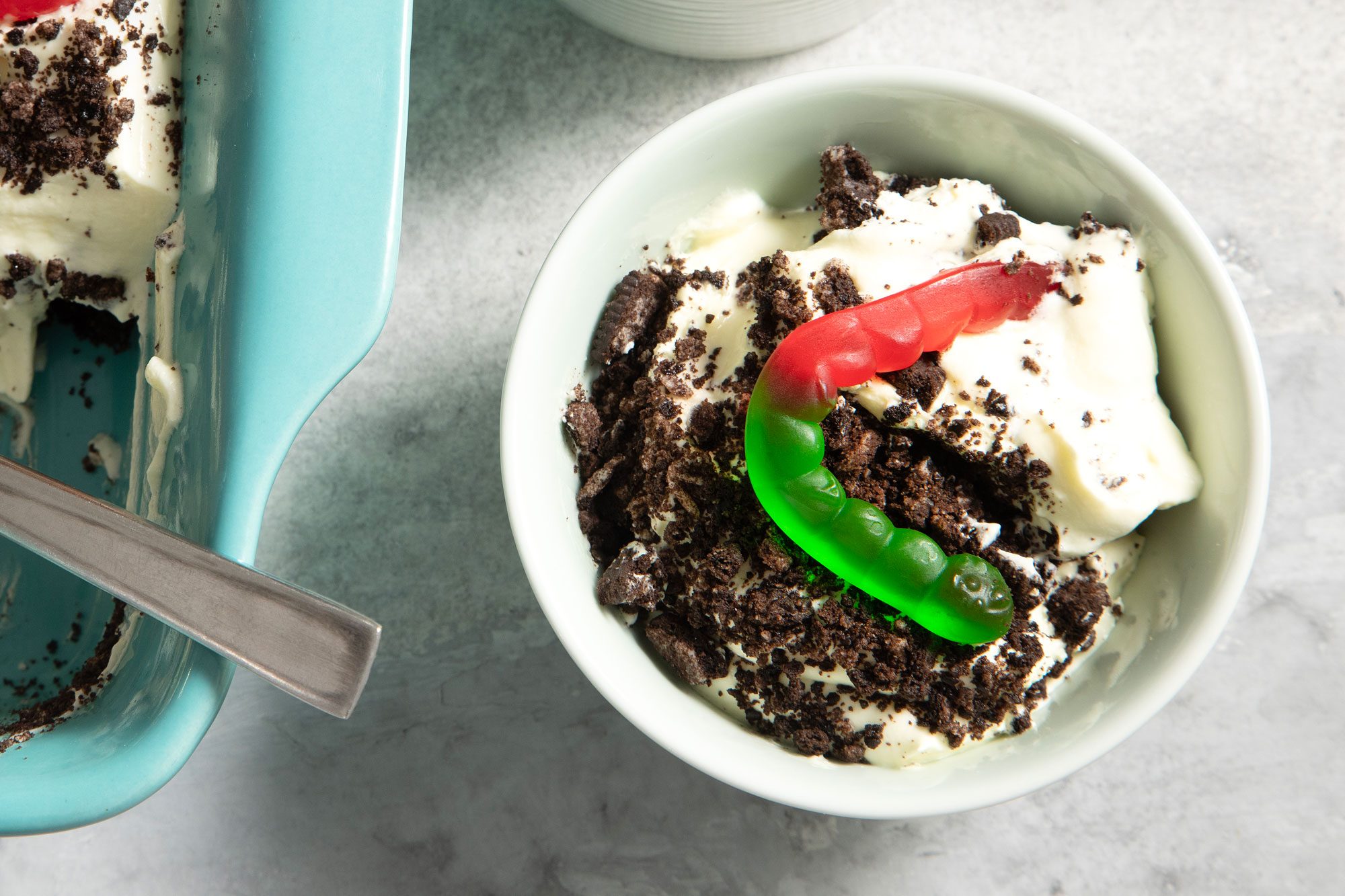 Dirt Dessert Topped With Gummy Worms Served in a Small Bowl on Grey Background