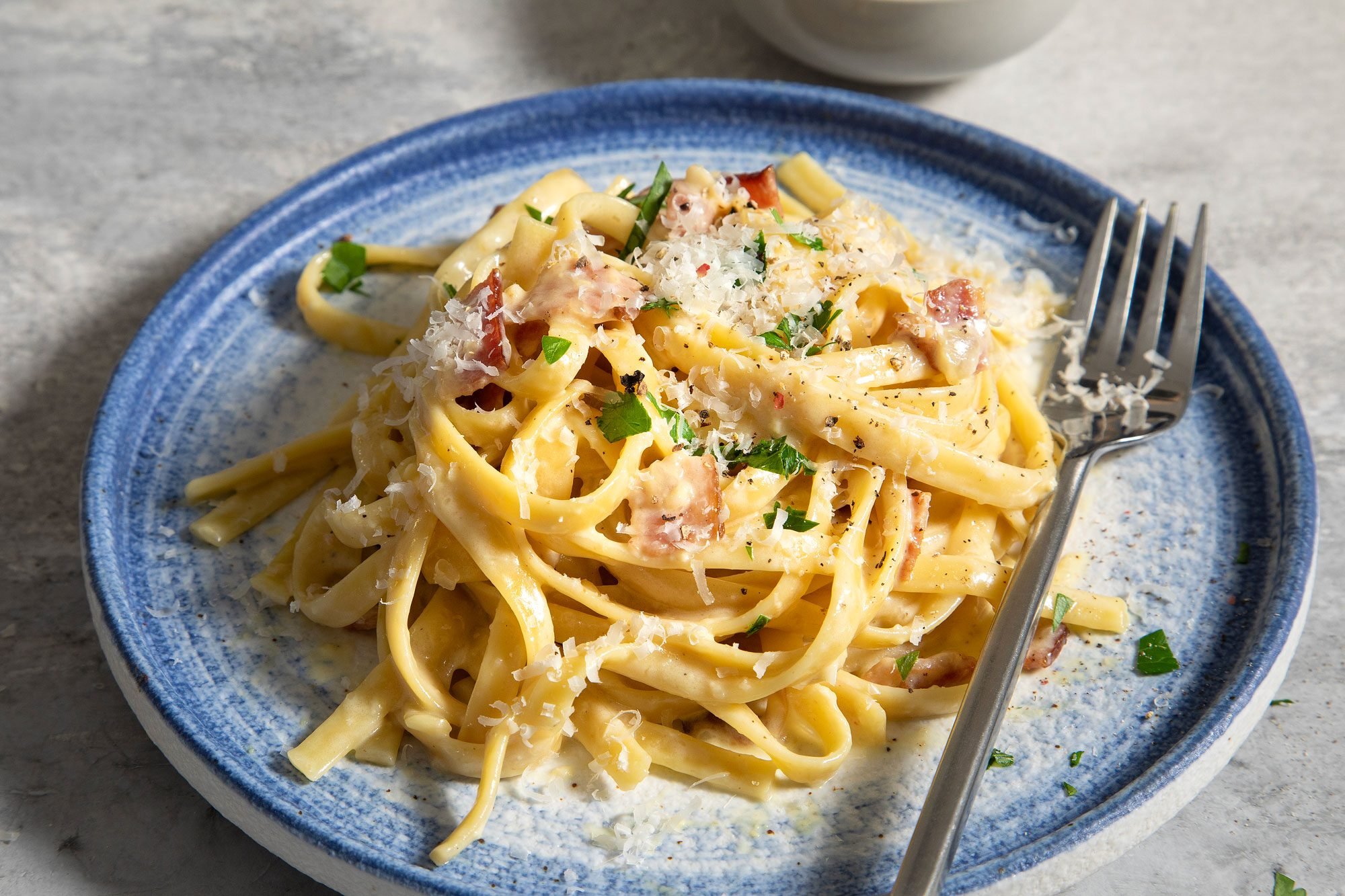 Fettuccine Carbonara with bacon, eggs, and Romano cheese served a dish with fork