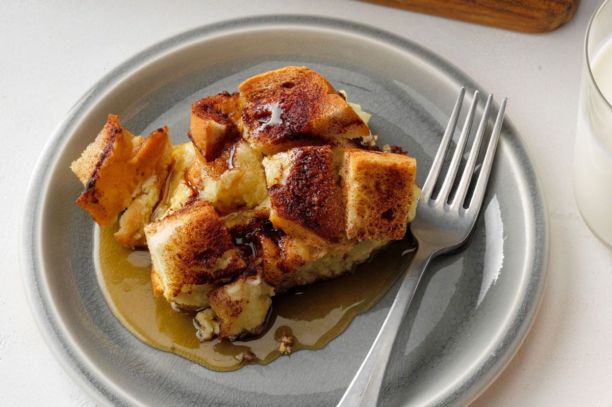 A delectable slice of French Toast Casserole, topped with a maple syrup, served on a plate with a fork