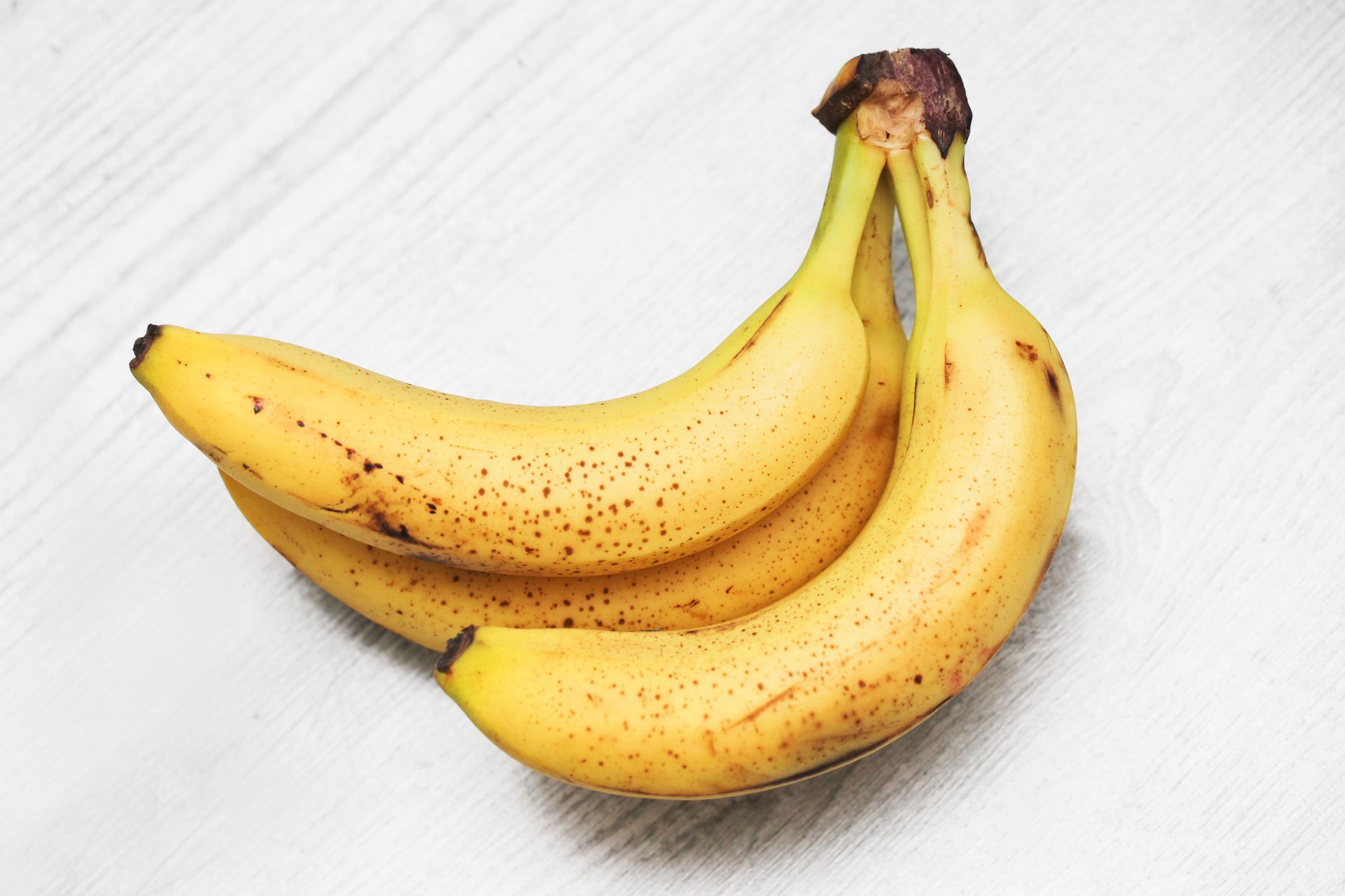 Bananas on gray wooden kitchen counter. Ripe bananas isolated on table of wood. Sunlight fruits.