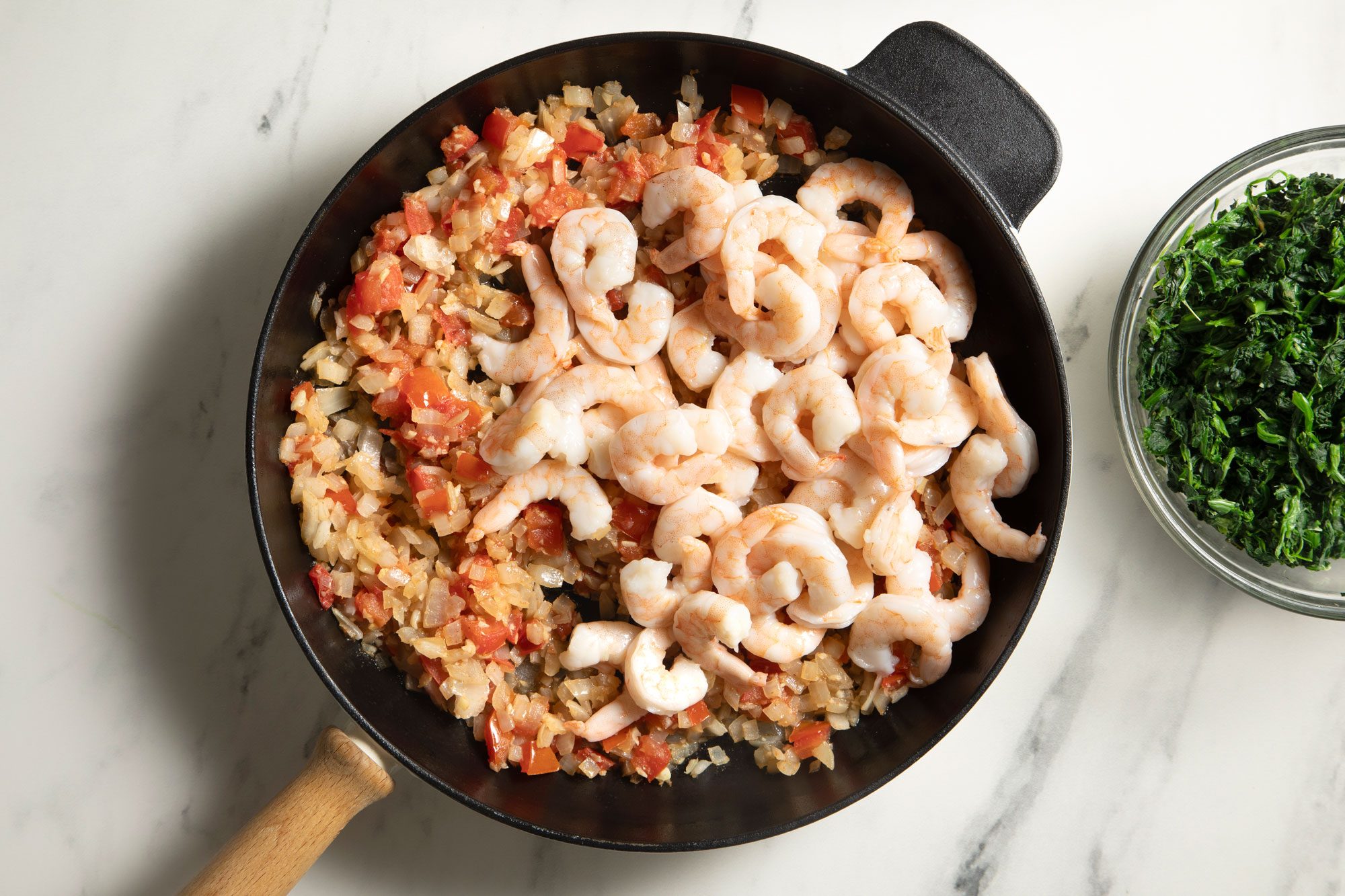 overhead shot; white background; In a large skillet, Add tomatoes, onions, garlic and cumin; cook and stir until onions are tender; Add shrimp;